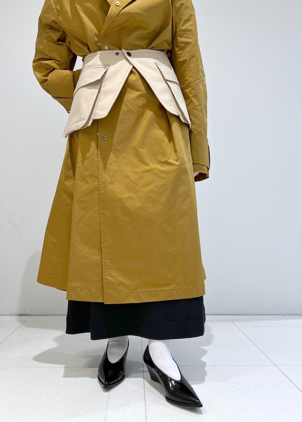 ブラウン系のステンカラーコート、ブラック系のパンプス、ベージュ系のベルトを着用したレディースの冬コーディネートの5枚目の写真