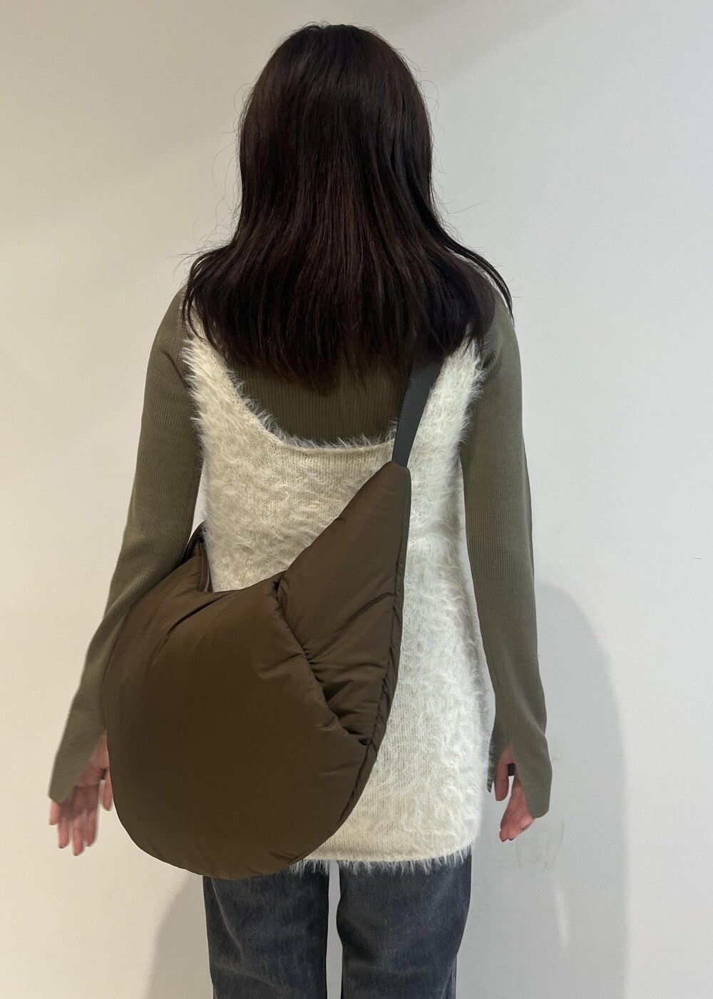 グレー系のデニムパンツ、ブラック系のパンプス、グリーン系のニット/セーターを着用したレディースの秋コーディネートの5枚目の写真