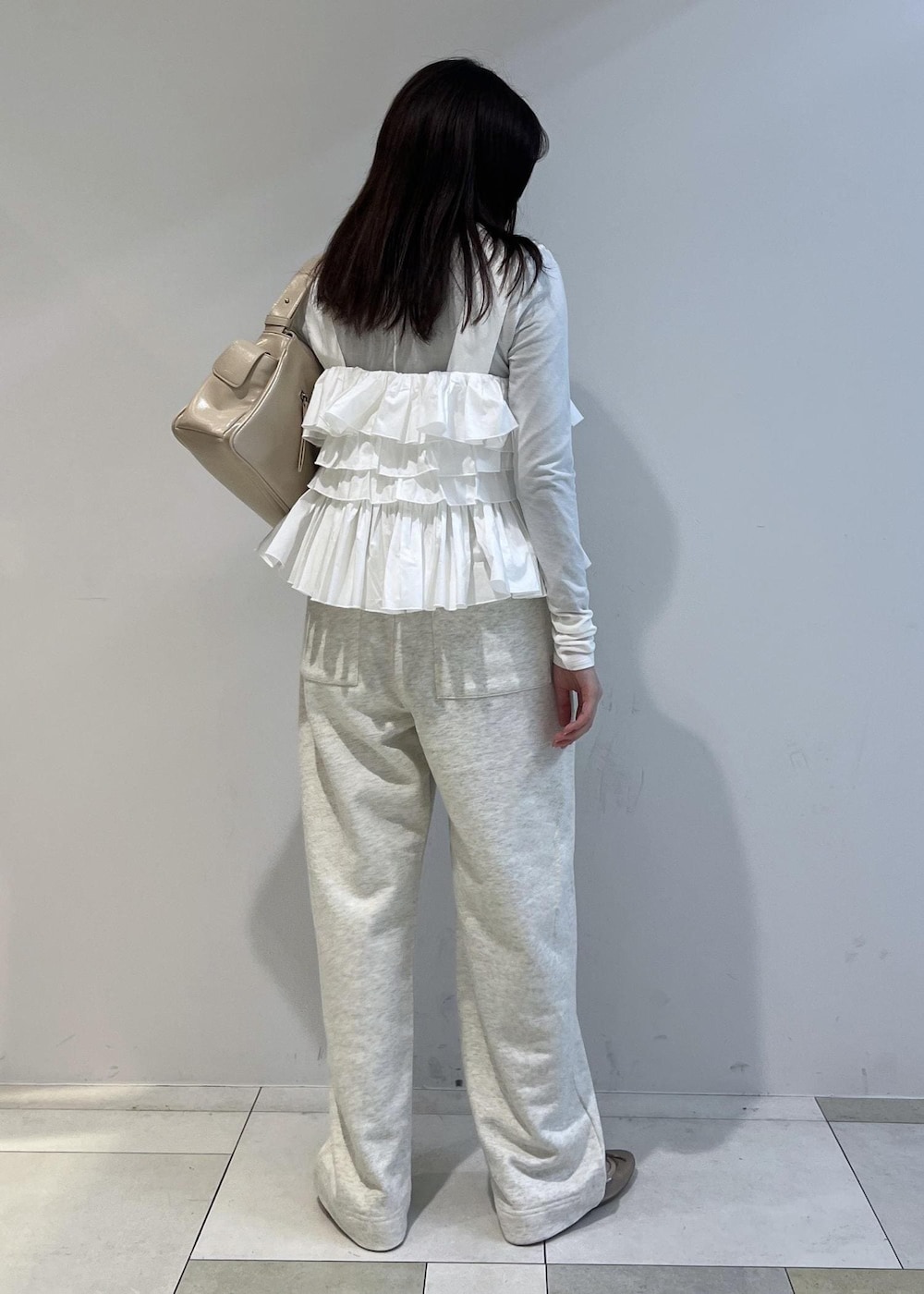 ホワイト系のスウェットパンツ、ベージュ系のショルダーバッグ、その他のバレエシューズを着用したレディースの冬コーディネートの2枚目の写真