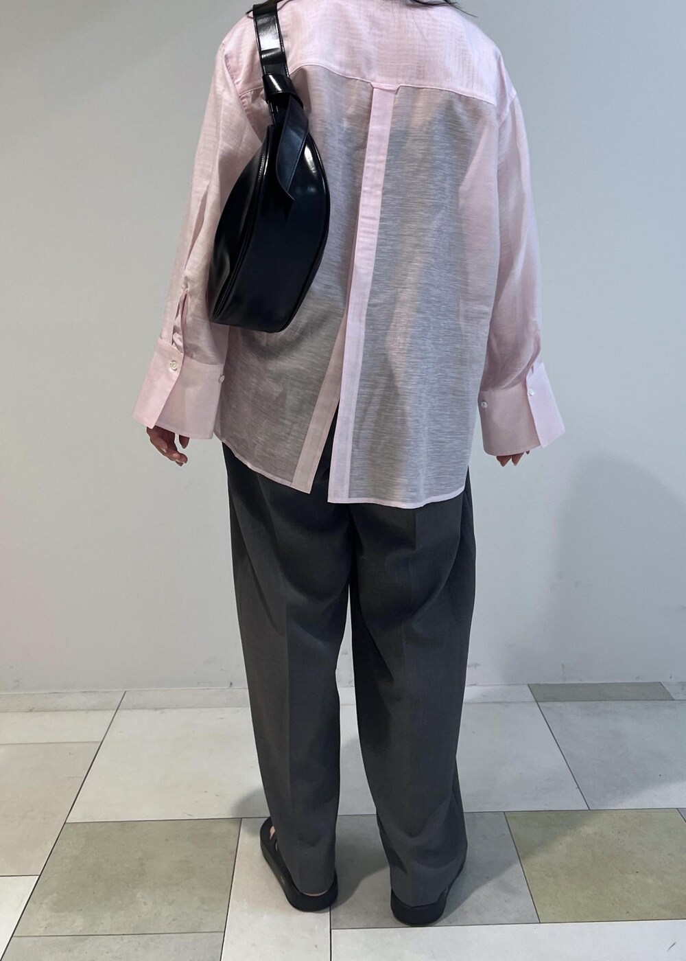 ブラック系のショルダーバッグ、ピンク系のシャツ/ブラウス、グレー系のスラックスを着用したレディースの春コーディネートの5枚目の写真