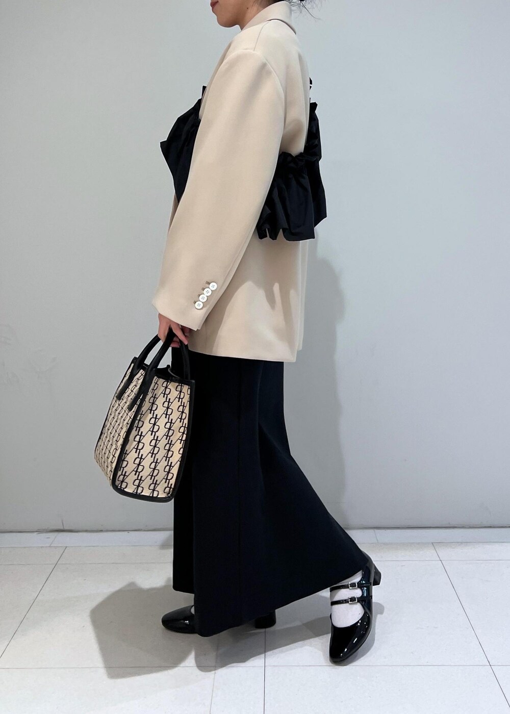 ブラック系のパンプス、ブラック系のワンピース、ベージュ系のテーラードジャケットを着用したレディースの冬コーディネートの2枚目の写真