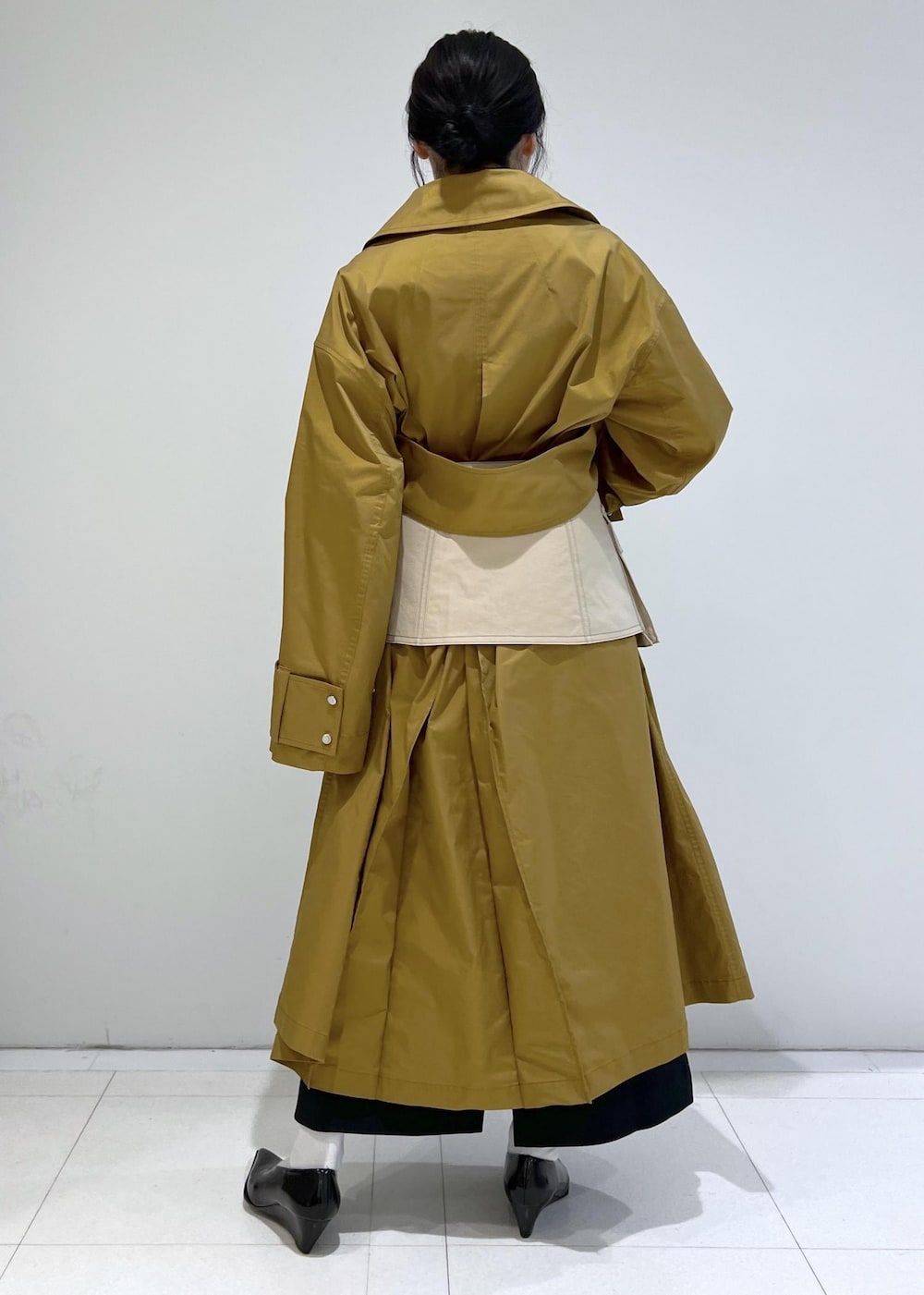 ブラウン系のステンカラーコート、ブラック系のパンプス、ベージュ系のベルトを着用したレディースの冬コーディネートの2枚目の写真