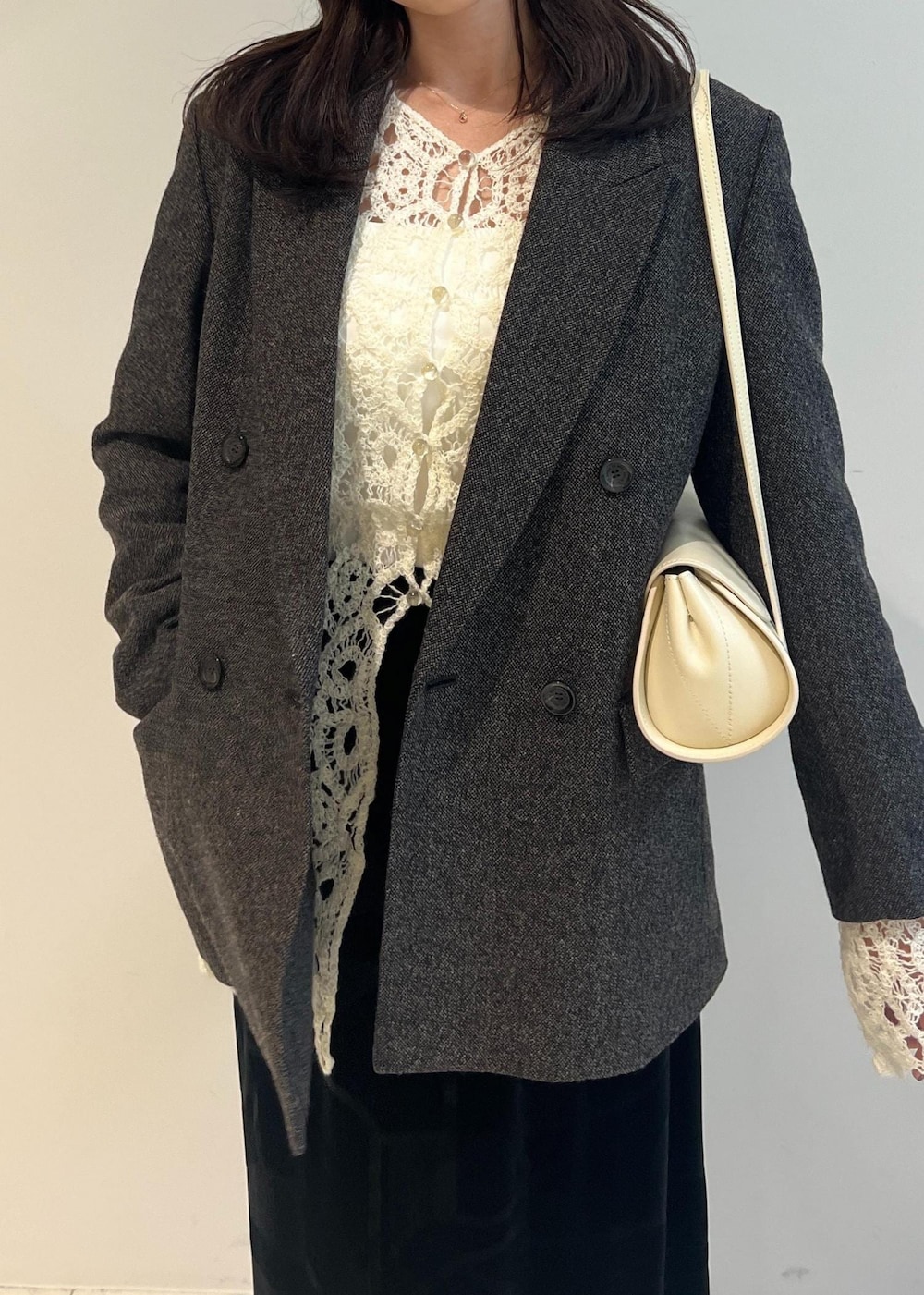 ブラック系のスカート、ブラック系のパンプス、ホワイト系のショルダーバッグを着用したレディースの秋コーディネートの3枚目の写真