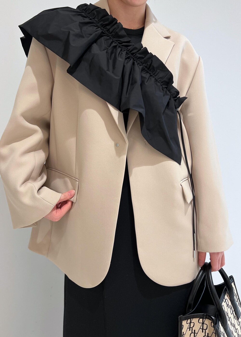 ブラック系のパンプス、ブラック系のワンピース、ベージュ系のテーラードジャケットを着用したレディースの冬コーディネートの4枚目の写真