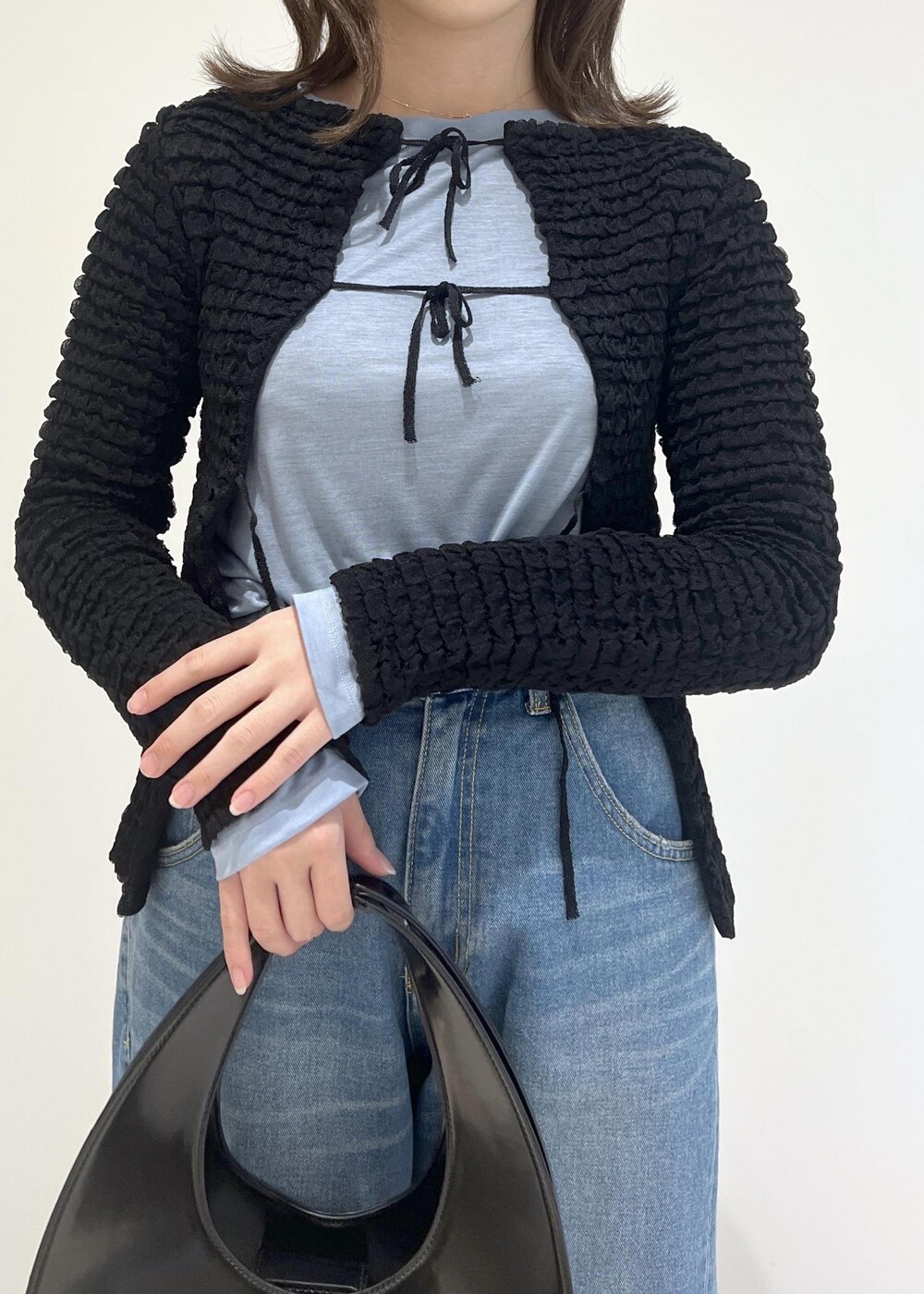 グリーン系のパンプス、ブラック系のハンドバッグ、ブルー系のデニムパンツを着用したレディースの秋コーディネートの2枚目の写真
