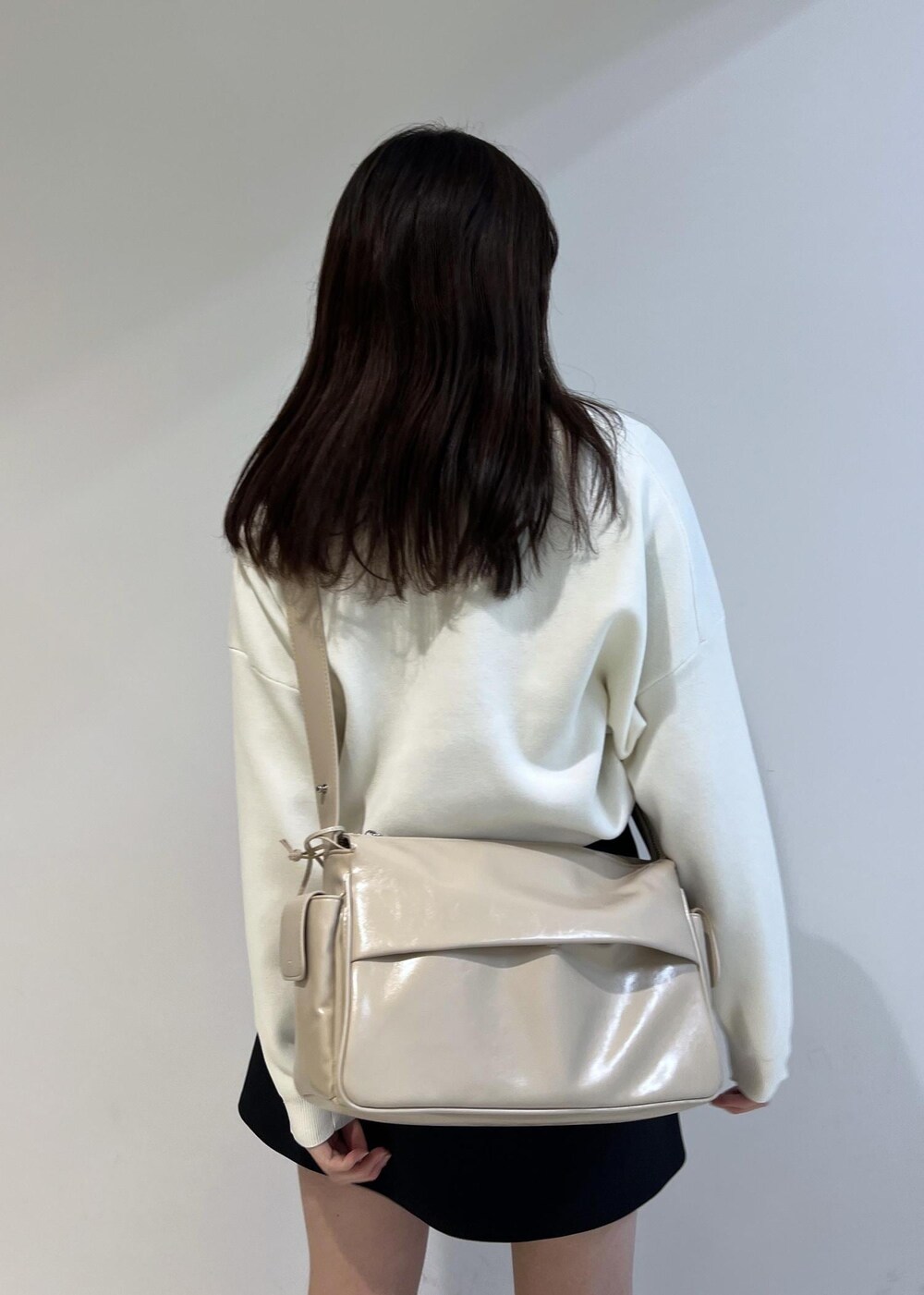 ブラック系のスカート、ベージュ系のショルダーバッグ、ホワイト系のニット/セーターを着用したレディースの冬コーディネートの3枚目の写真