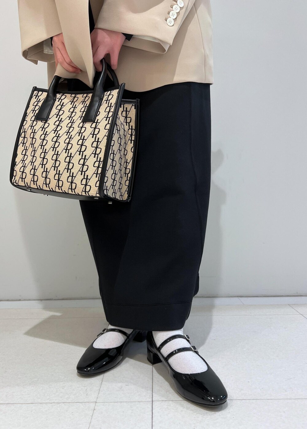 ブラック系のパンプス、ブラック系のワンピース、ベージュ系のテーラードジャケットを着用したレディースの冬コーディネートの5枚目の写真