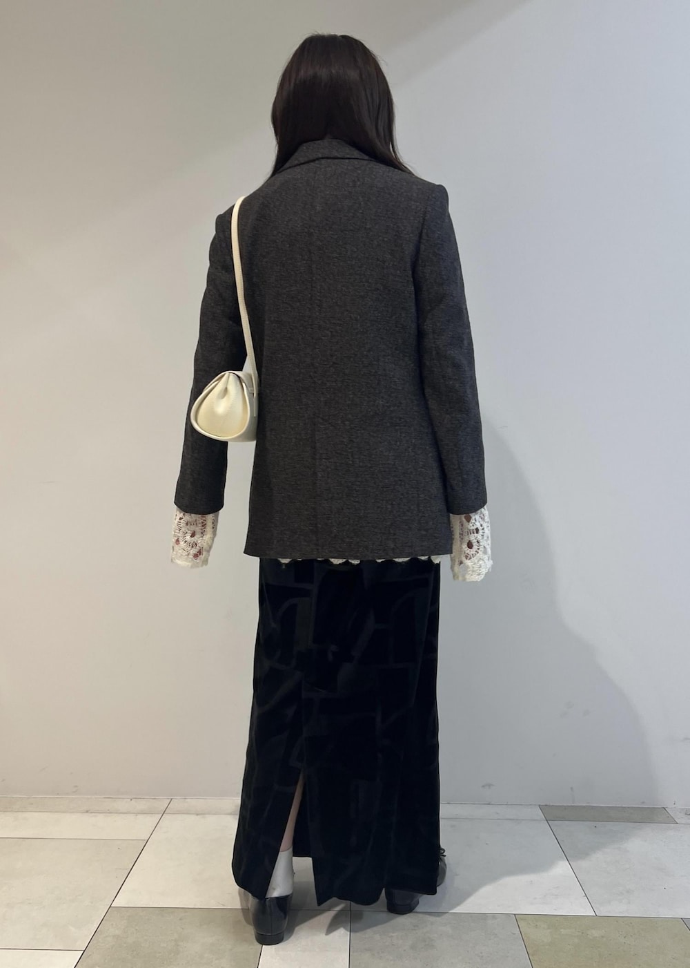 ブラック系のスカート、ブラック系のパンプス、ホワイト系のショルダーバッグを着用したレディースの秋コーディネートの5枚目の写真