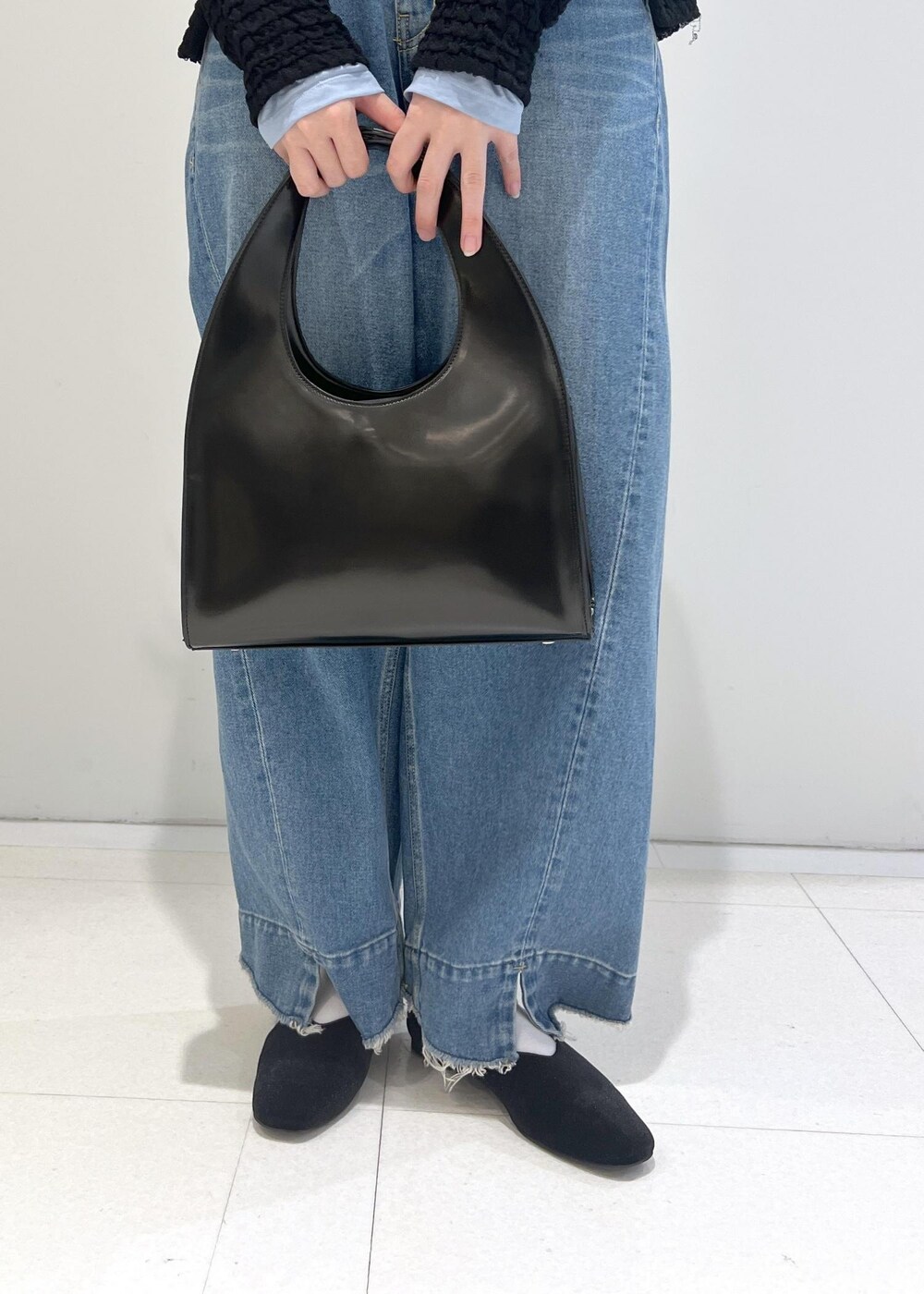 グリーン系のパンプス、ブラック系のハンドバッグ、ブルー系のデニムパンツを着用したレディースの秋コーディネートの5枚目の写真