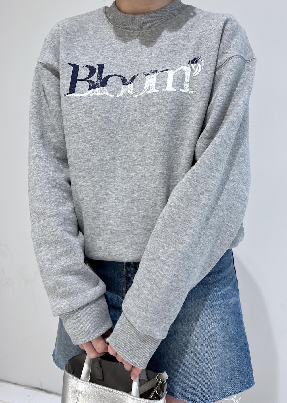 グレー系のスウェット、ブラック系のパンプス、ブルー系のデニムスカートを着用したレディースの冬コーディネートの3枚目の写真