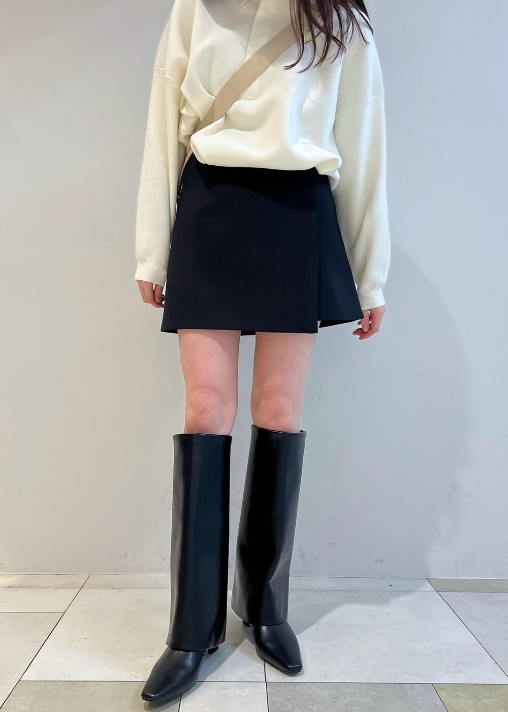 ブラック系のスカート、ベージュ系のショルダーバッグ、ホワイト系のニット/セーターを着用したレディースの冬コーディネートの5枚目の写真