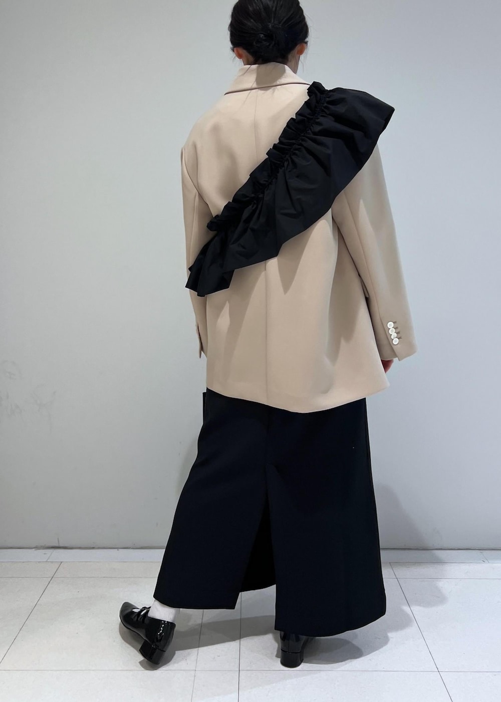 ブラック系のパンプス、ブラック系のワンピース、ベージュ系のテーラードジャケットを着用したレディースの冬コーディネートの3枚目の写真