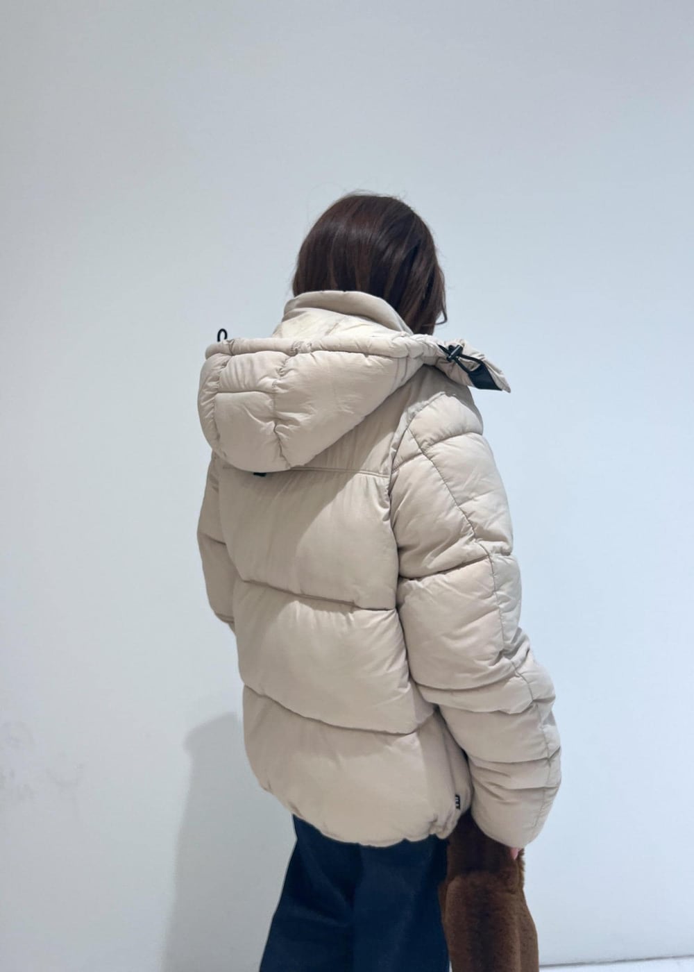 ブルー系のデニムパンツ、ベージュ系のダウンジャケット/コート、ベージュ系のモカシン/デッキシューズを着用したレディースの秋コーディネートの6枚目の写真