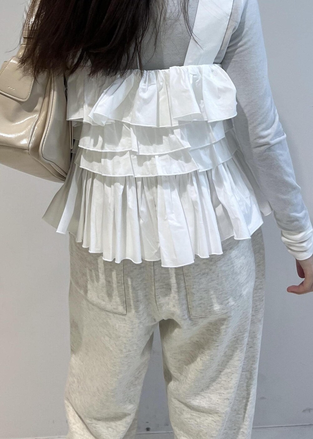 ホワイト系のスウェットパンツ、ベージュ系のショルダーバッグ、その他のバレエシューズを着用したレディースの冬コーディネートの5枚目の写真
