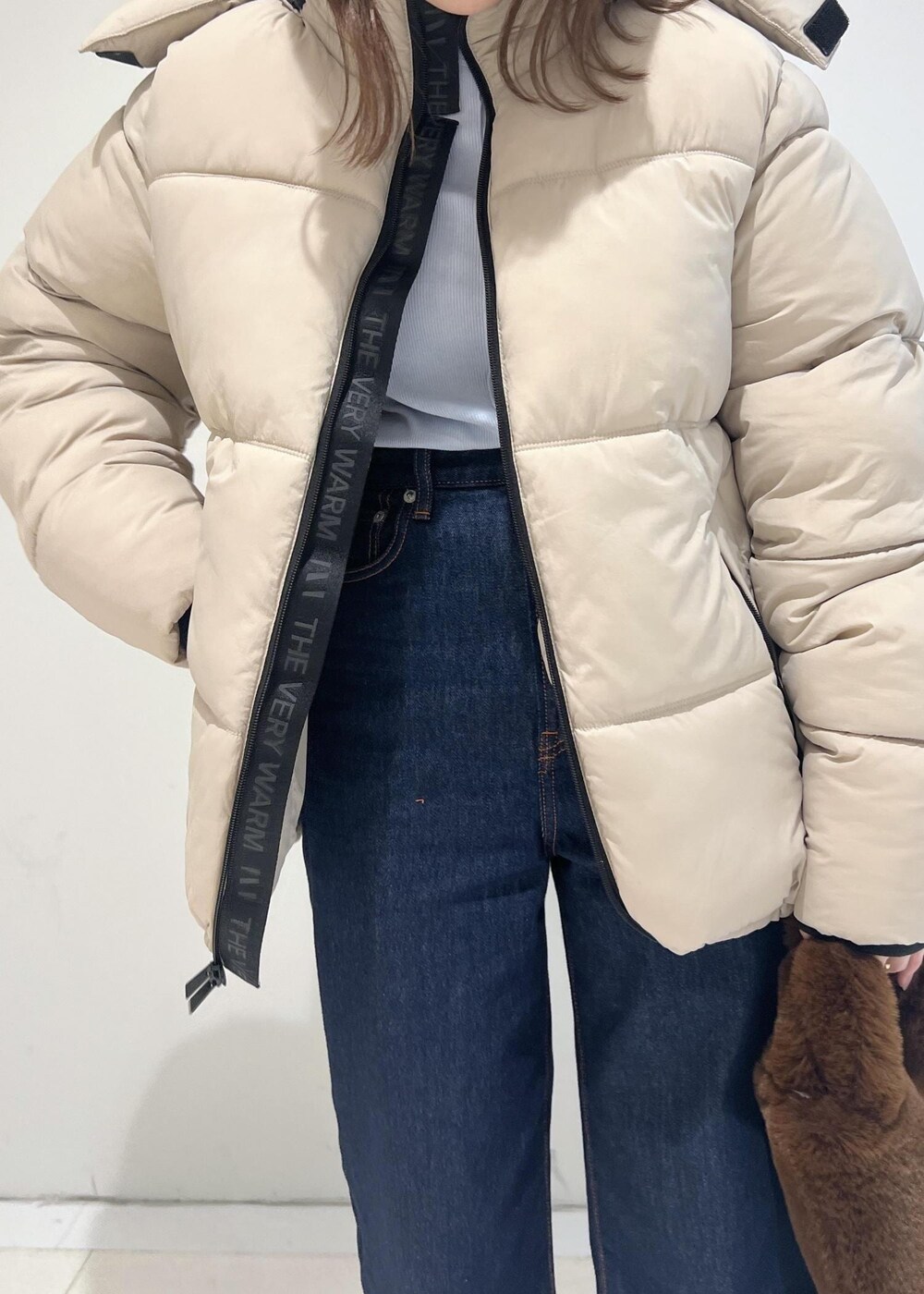 ブルー系のデニムパンツ、ベージュ系のダウンジャケット/コート、ベージュ系のモカシン/デッキシューズを着用したレディースの秋コーディネートの5枚目の写真