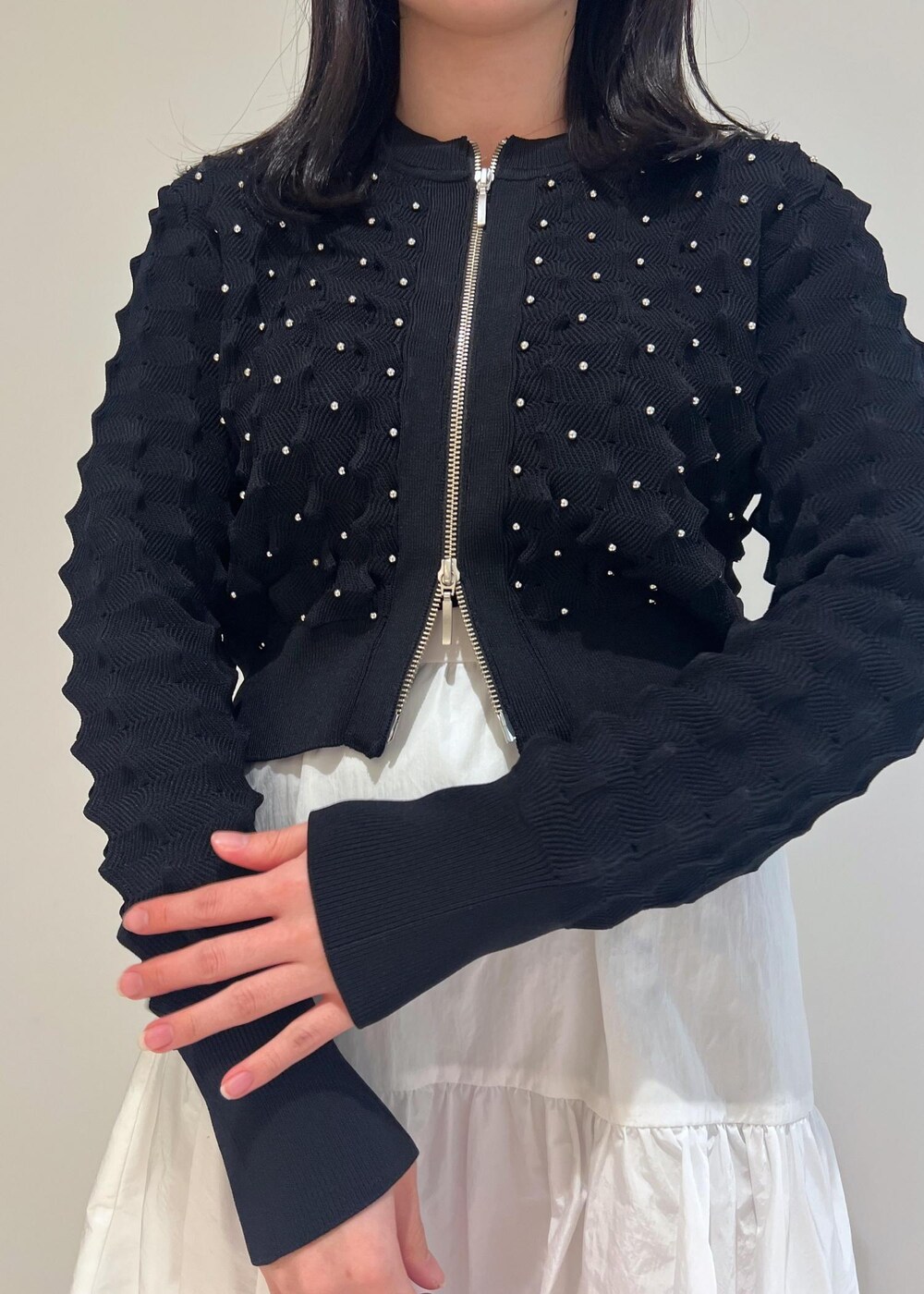 パープル系のハンドバッグ、シルバー系のパンプス、ホワイト系のスカートを着用したレディースの冬コーディネートの3枚目の写真