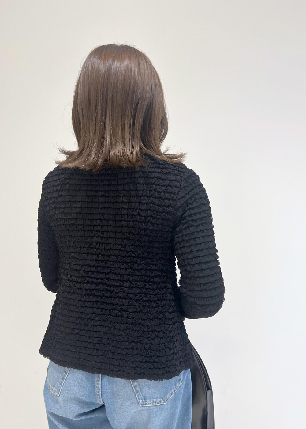 グリーン系のパンプス、ブラック系のハンドバッグ、ブルー系のデニムパンツを着用したレディースの秋コーディネートの4枚目の写真