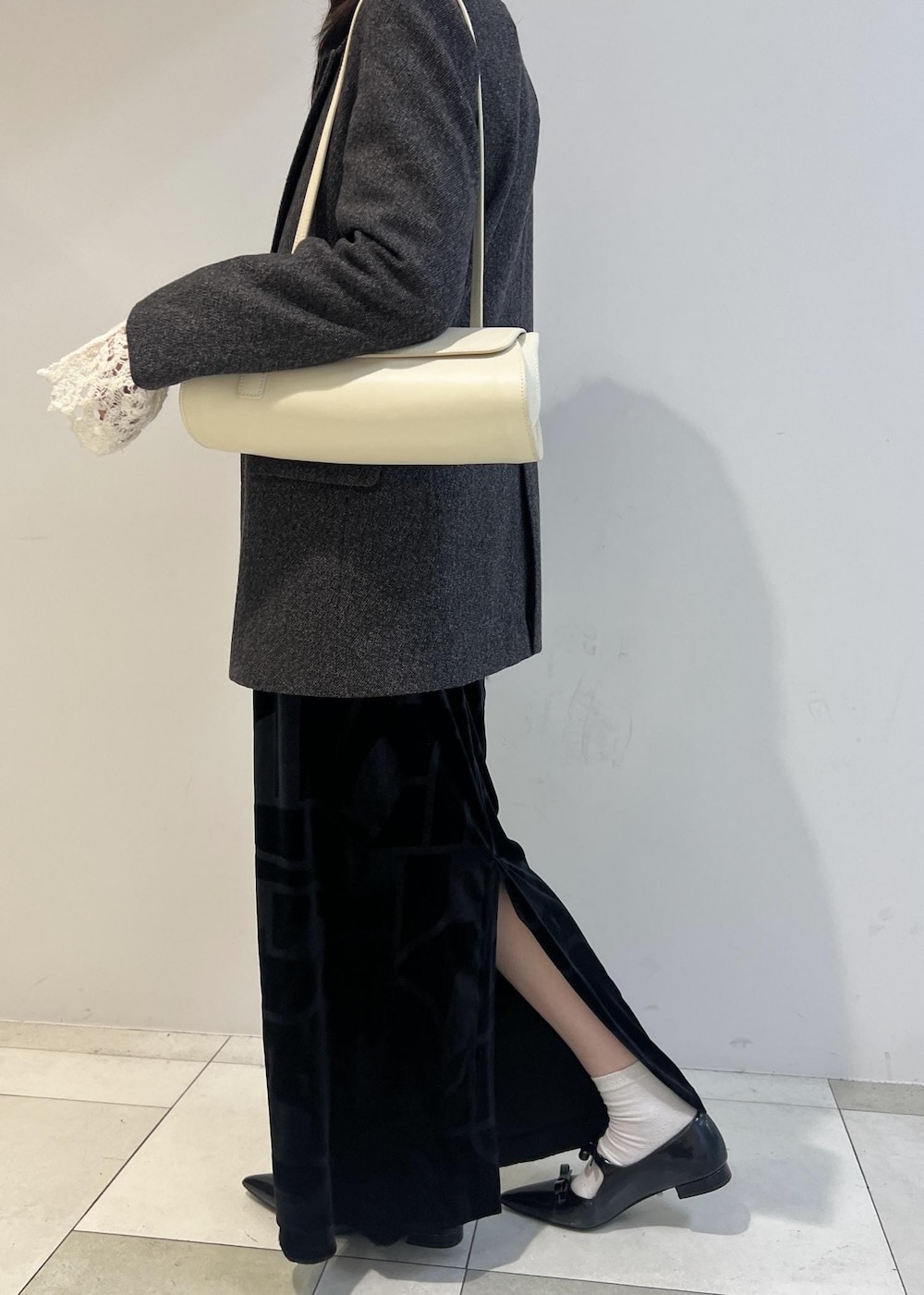 ブラック系のスカート、ブラック系のパンプス、ホワイト系のショルダーバッグを着用したレディースの秋コーディネートの4枚目の写真