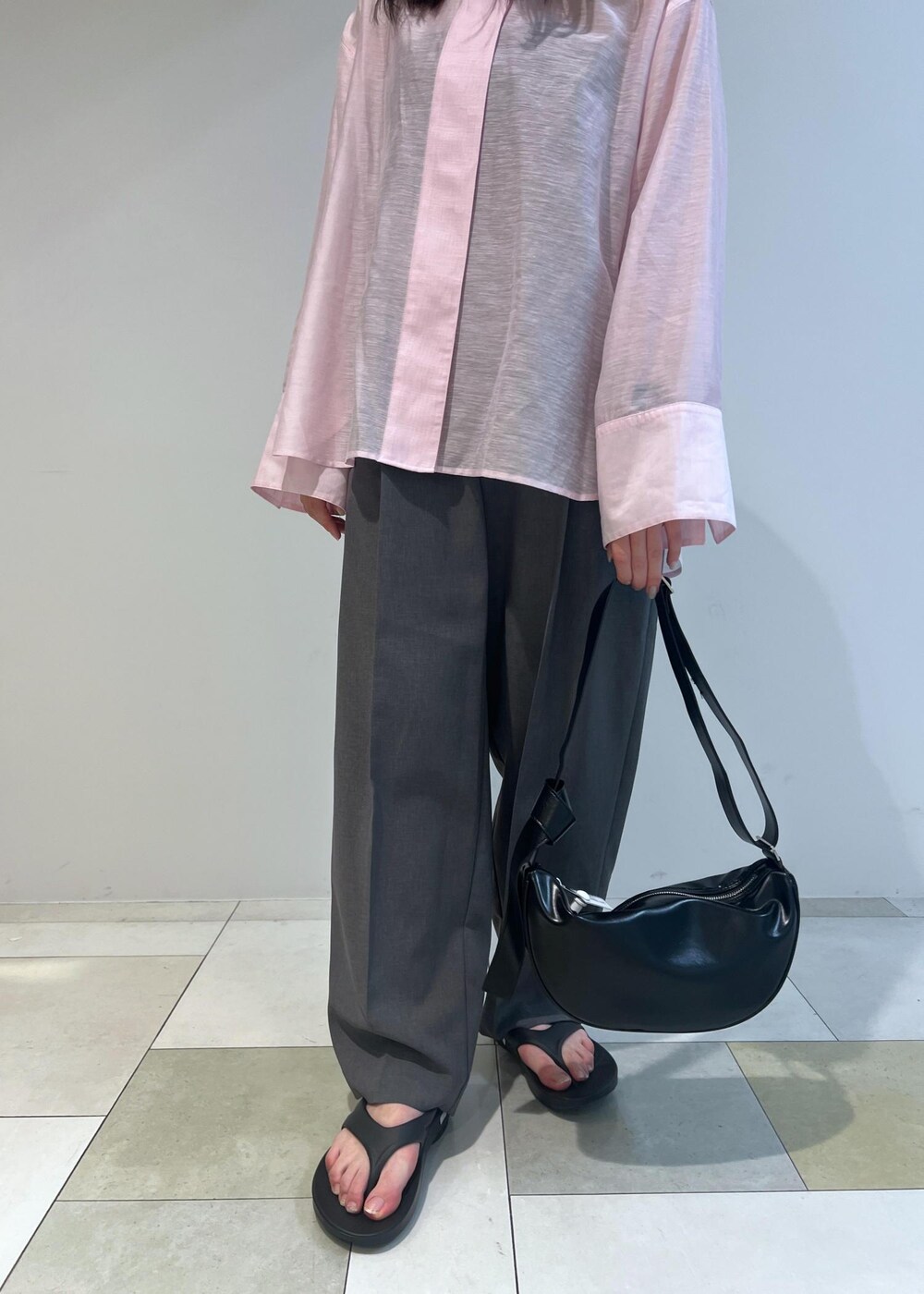 ブラック系のショルダーバッグ、ピンク系のシャツ/ブラウス、グレー系のスラックスを着用したレディースの春コーディネートの3枚目の写真