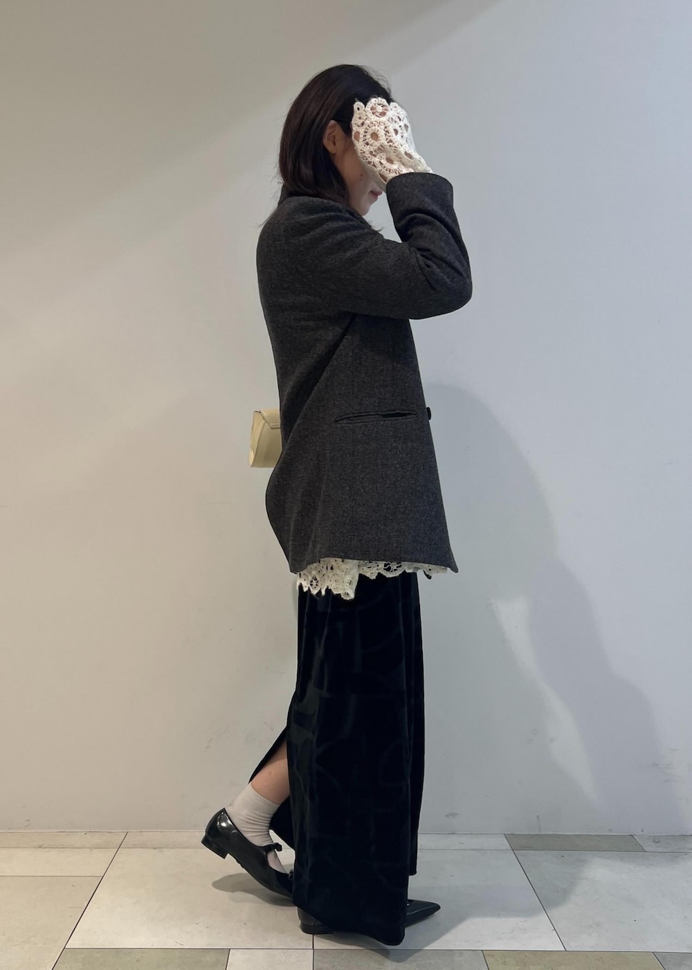 ブラック系のスカート、ブラック系のパンプス、ホワイト系のショルダーバッグを着用したレディースの秋コーディネートの2枚目の写真