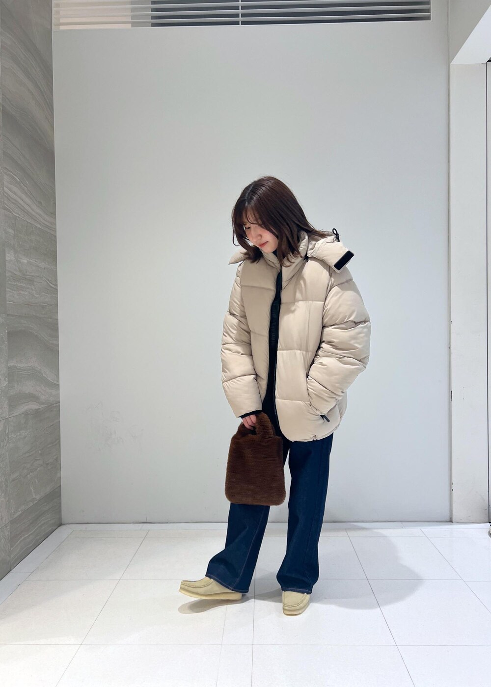 ブルー系のデニムパンツ、ベージュ系のダウンジャケット/コート、ベージュ系のモカシン/デッキシューズを着用したレディースの秋コーディネートの3枚目の写真