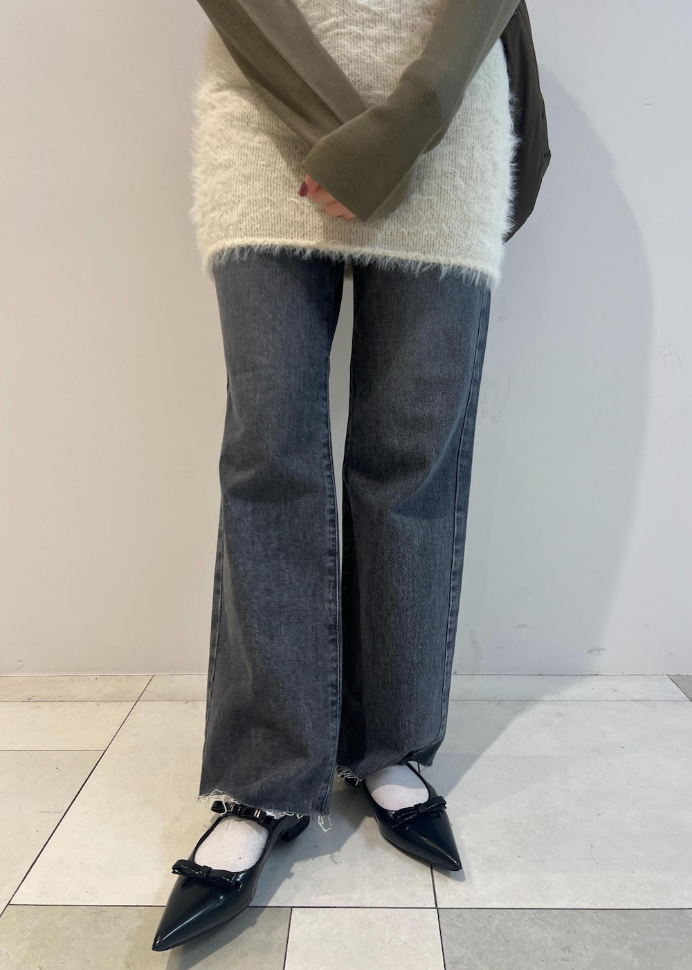 グレー系のデニムパンツ、ブラック系のパンプス、グリーン系のニット/セーターを着用したレディースの秋コーディネートの6枚目の写真