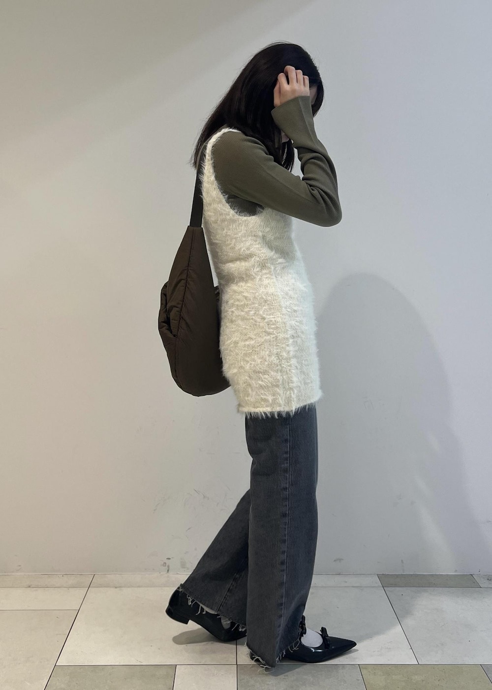 グレー系のデニムパンツ、ブラック系のパンプス、グリーン系のニット/セーターを着用したレディースの秋コーディネートの2枚目の写真