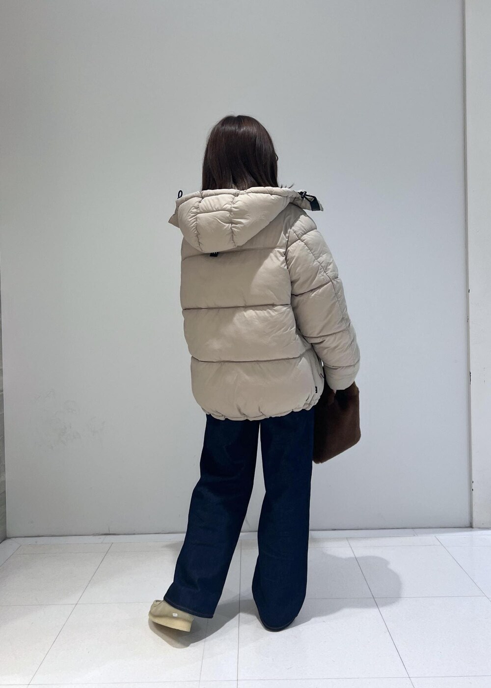 ブルー系のデニムパンツ、ベージュ系のダウンジャケット/コート、ベージュ系のモカシン/デッキシューズを着用したレディースの秋コーディネートの4枚目の写真
