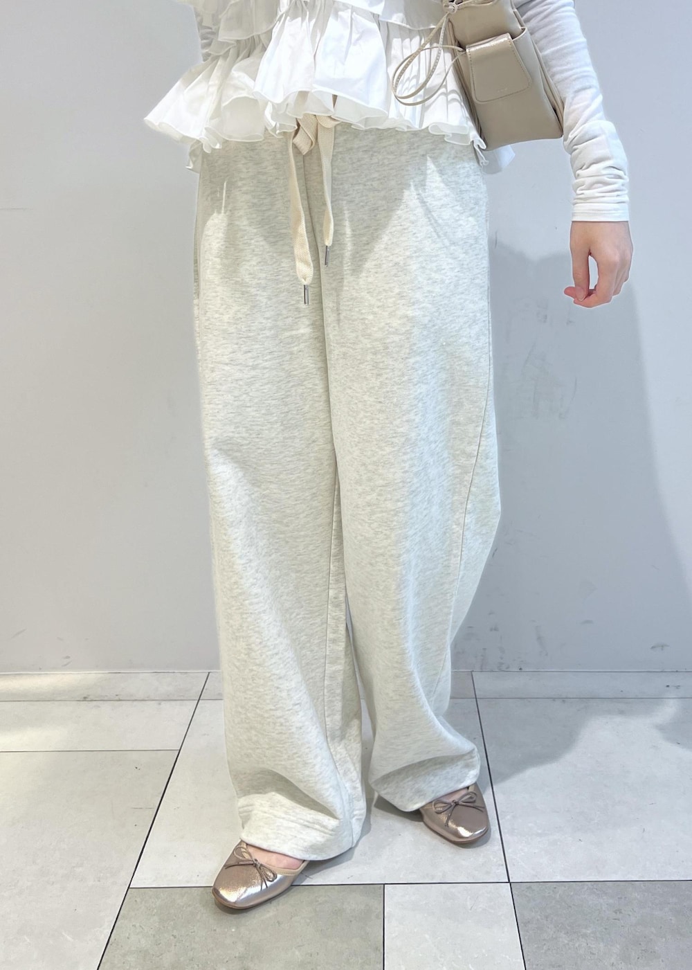 ホワイト系のスウェットパンツ、ベージュ系のショルダーバッグ、その他のバレエシューズを着用したレディースの冬コーディネートの6枚目の写真