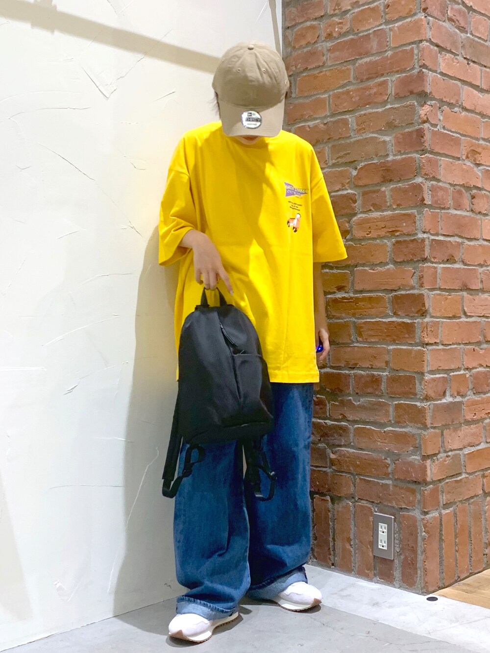 イエロー系のTシャツ/カットソー、ブルー系のデニムパンツ、ブラック系のバックパック/リュックを着用したレディースの夏コーディネートの2枚目の写真