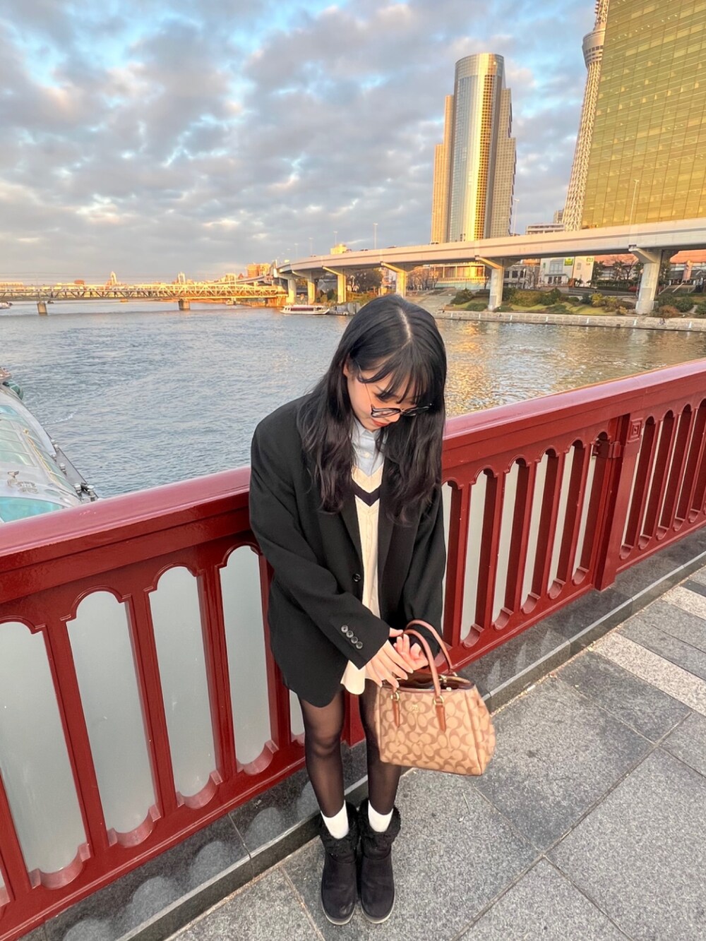 ブラック系のノーカラージャケット、ブラウン系のショルダーバッグ、ホワイト系のニット/セーターを着用したレディースの冬コーディネートの2枚目の写真