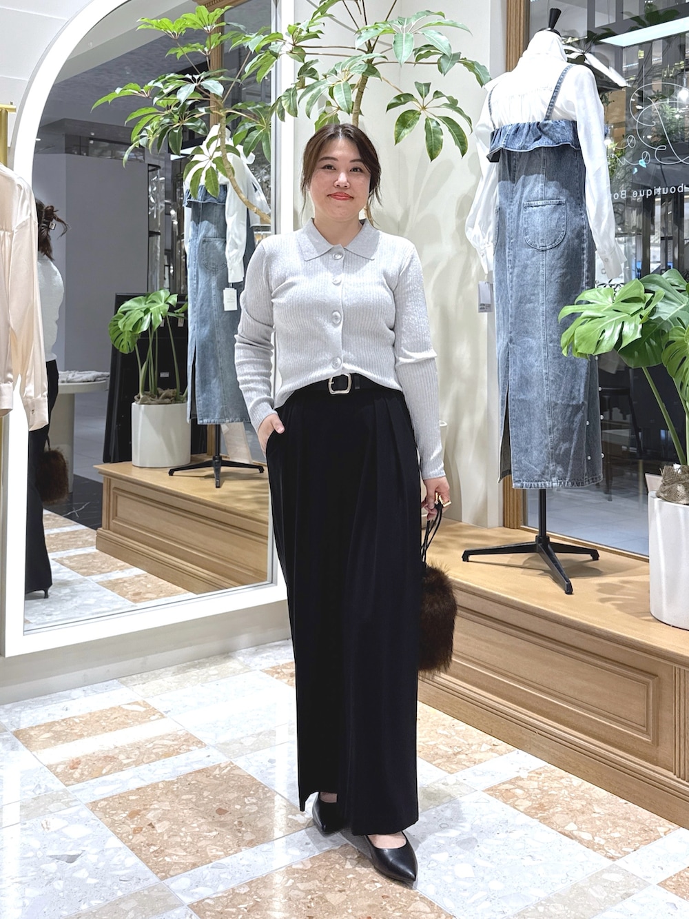 グレー系のニット/セーター、ブラック系のスラックス、ブラウン系のトートバッグを着用したレディースの秋コーディネートの2枚目の写真