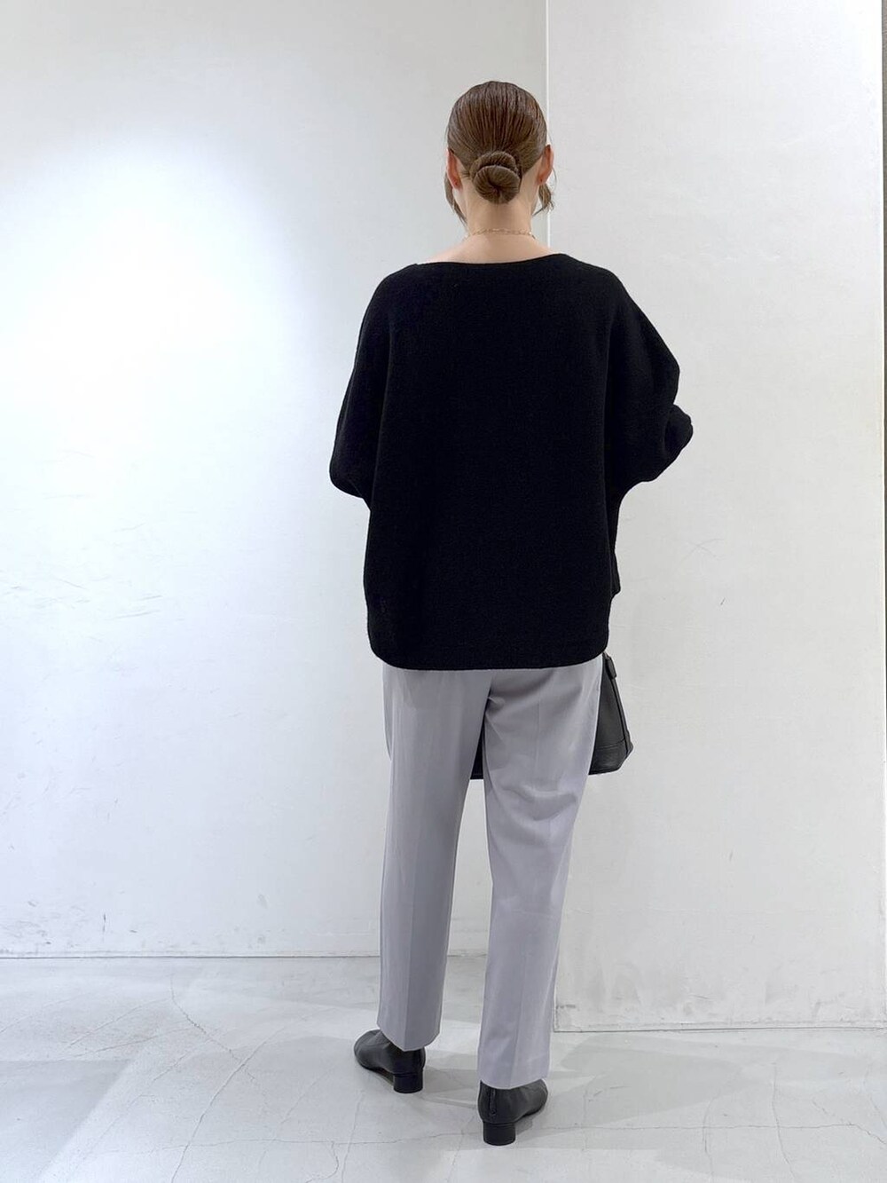 ブラック系のニット/セーター、ブラック系のボストンバッグ、グレー系のスラックスを着用したレディースの秋コーディネートの6枚目の写真