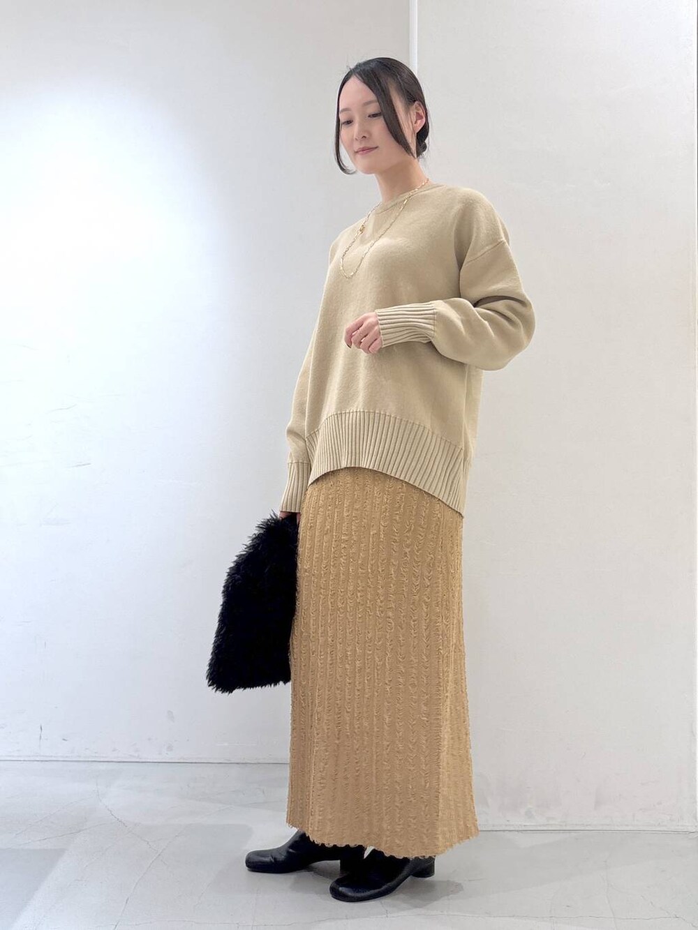 ブラック系のトートバッグ、ベージュ系のスカート、ベージュ系のニット/セーターを着用したレディースの冬コーディネートの3枚目の写真