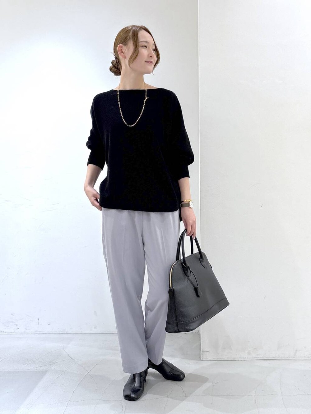 ブラック系のニット/セーター、ブラック系のボストンバッグ、グレー系のスラックスを着用したレディースの秋コーディネートの3枚目の写真