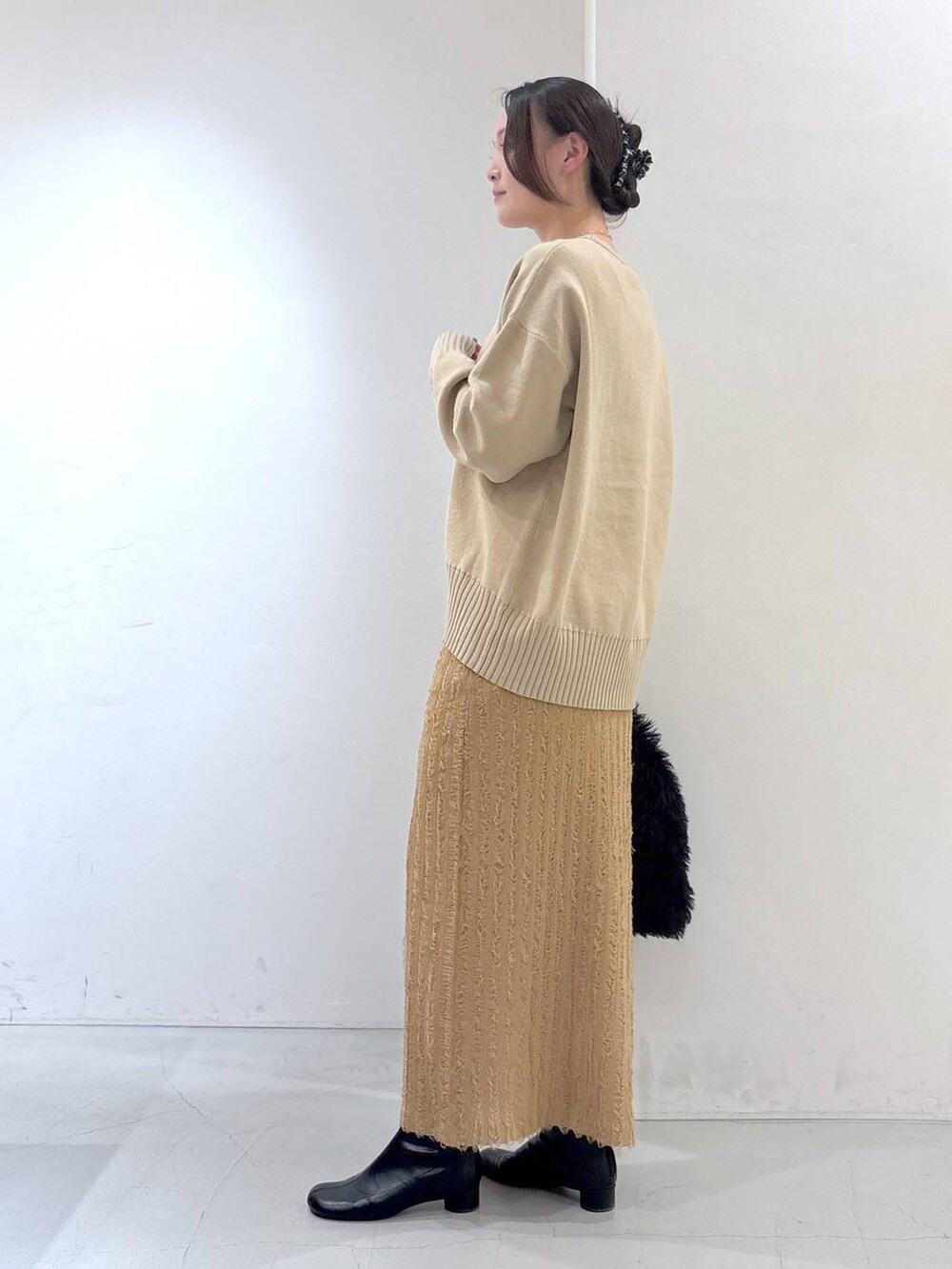 ブラック系のトートバッグ、ベージュ系のスカート、ベージュ系のニット/セーターを着用したレディースの冬コーディネートの4枚目の写真