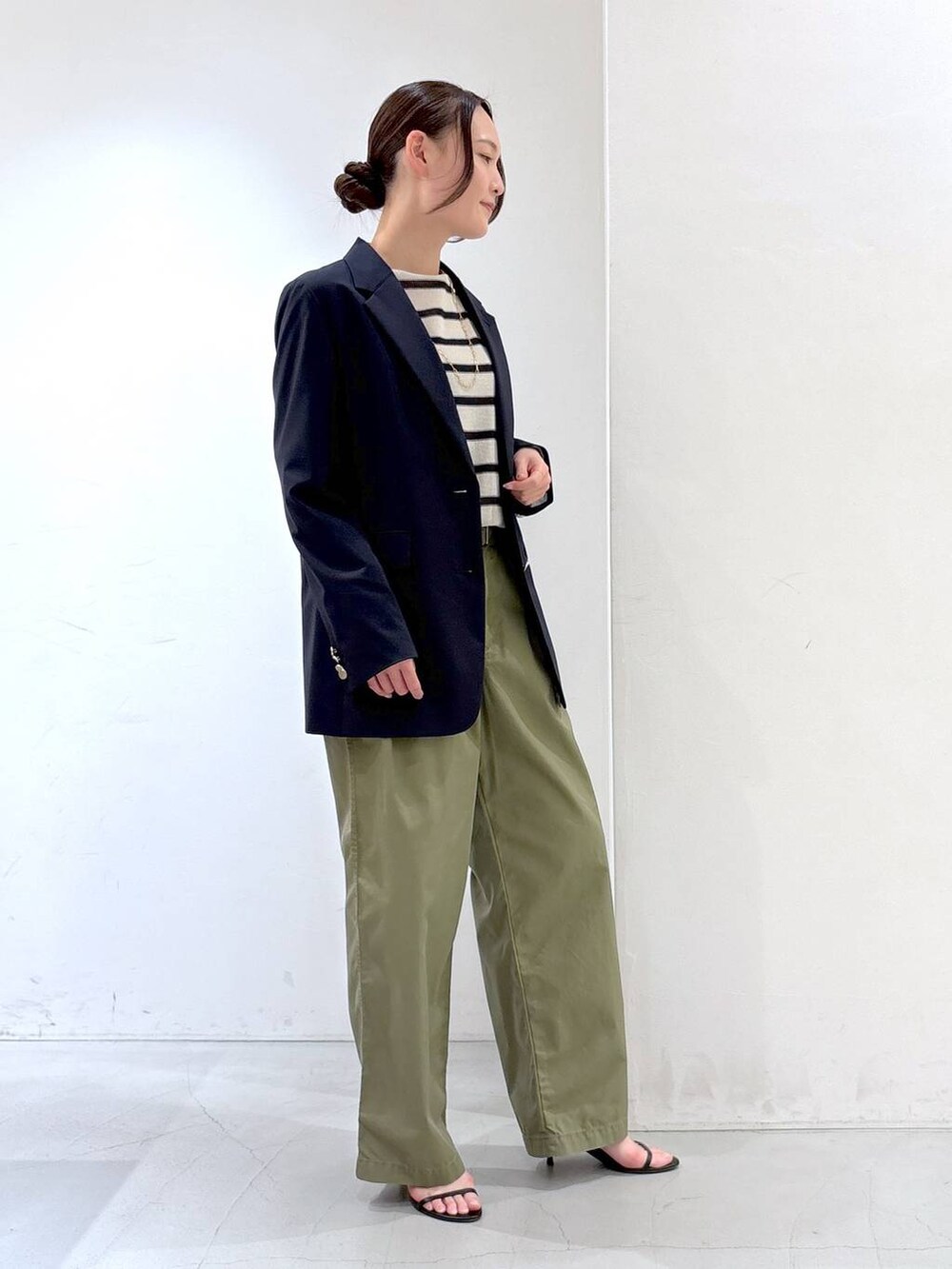 グリーン系のチノパンツ、ブルー系のテーラードジャケット、ホワイト系のニット/セーターを着用したレディースの春コーディネートの3枚目の写真