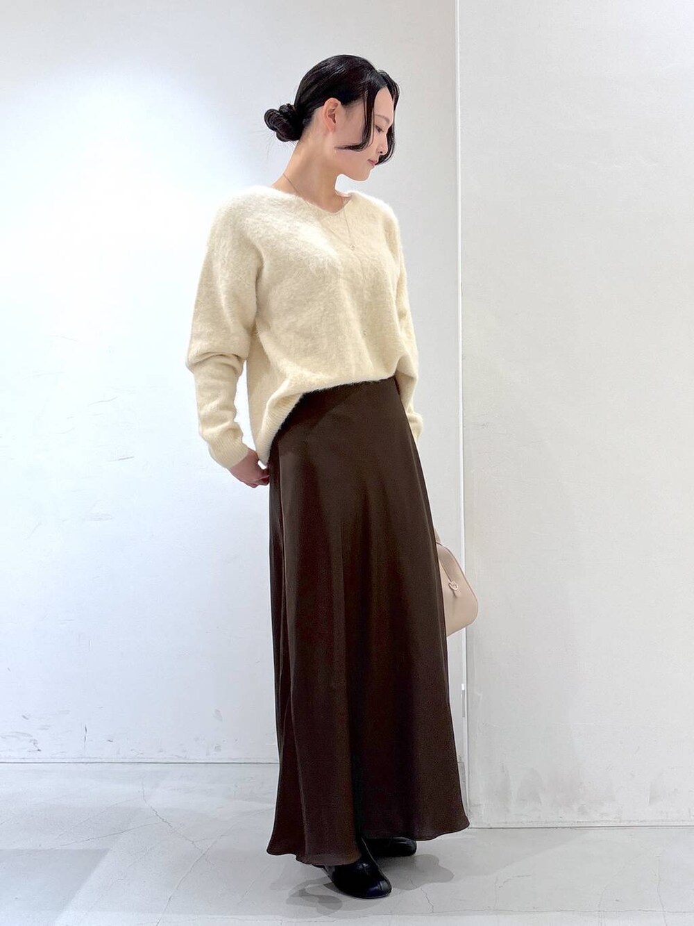 ベージュ系のニット/セーター、ベージュ系のボストンバッグ、ブラウン系のスカートを着用したレディースの冬コーディネートの2枚目の写真