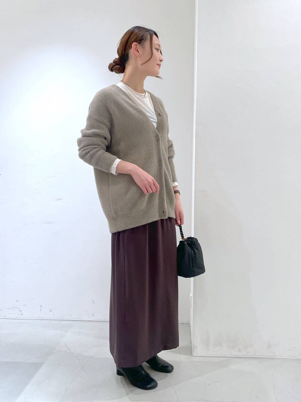 ホワイト系のTシャツ/カットソー、ブラウン系のカーディガン/ボレロ、ブラウン系のスカートを着用したレディースの冬コーディネートの3枚目の写真