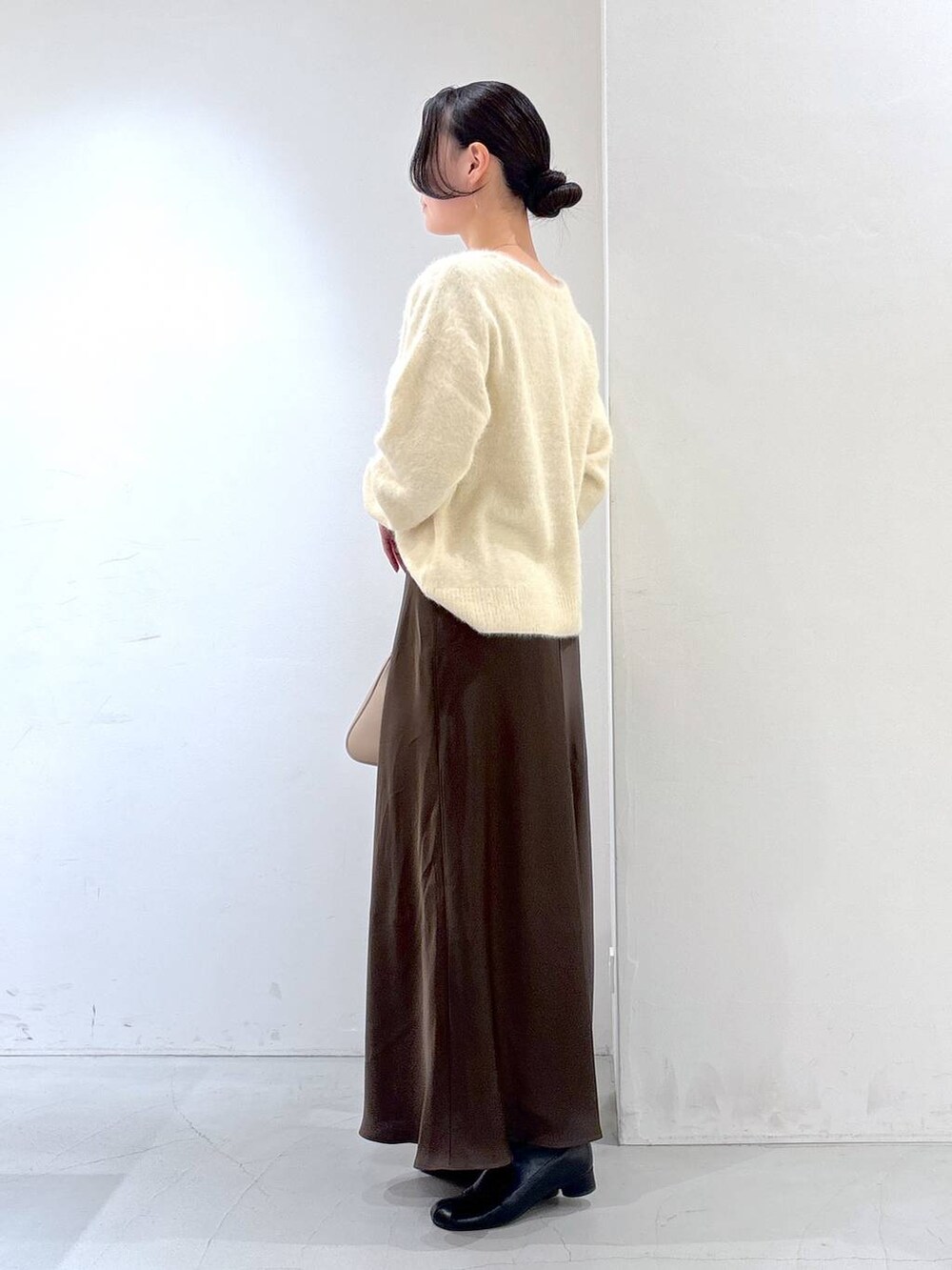 ベージュ系のニット/セーター、ベージュ系のボストンバッグ、ブラウン系のスカートを着用したレディースの冬コーディネートの3枚目の写真