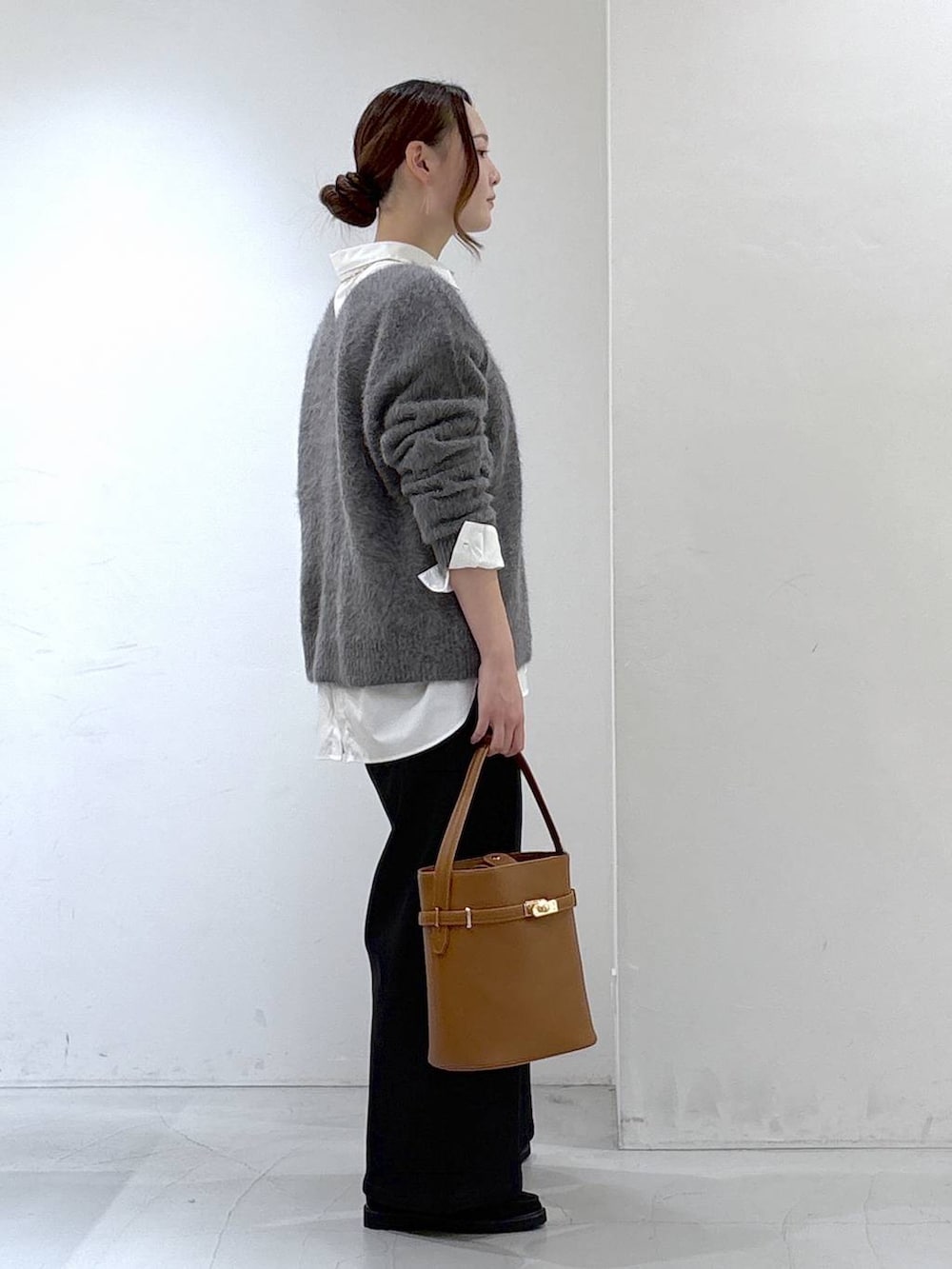 グレー系のニット/セーター、ホワイト系のシャツ/ブラウス、ブラック系のデニムパンツを着用したレディースの秋コーディネートの3枚目の写真