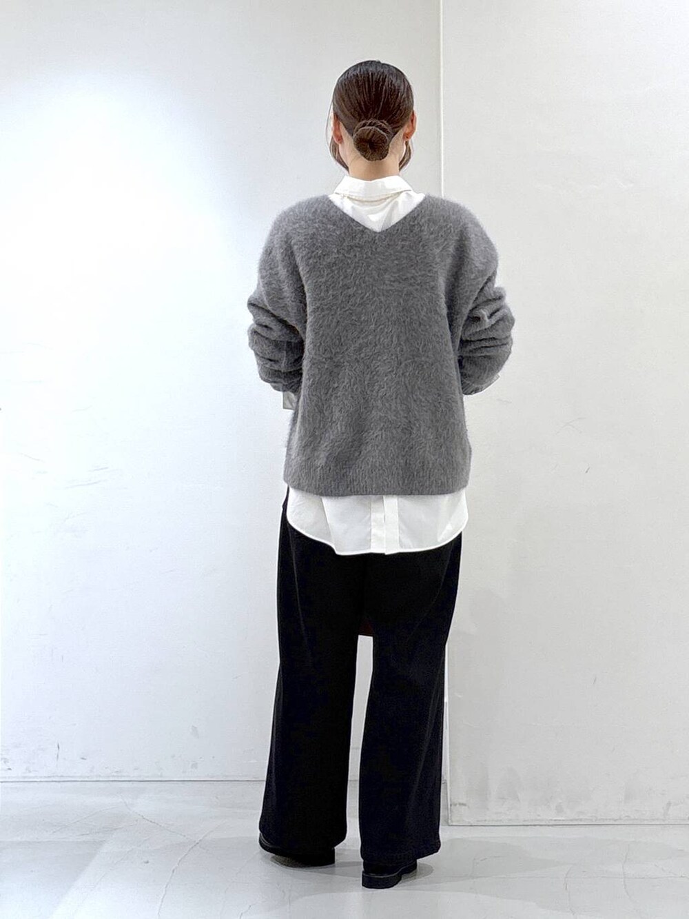 グレー系のニット/セーター、ホワイト系のシャツ/ブラウス、ブラック系のデニムパンツを着用したレディースの秋コーディネートの4枚目の写真