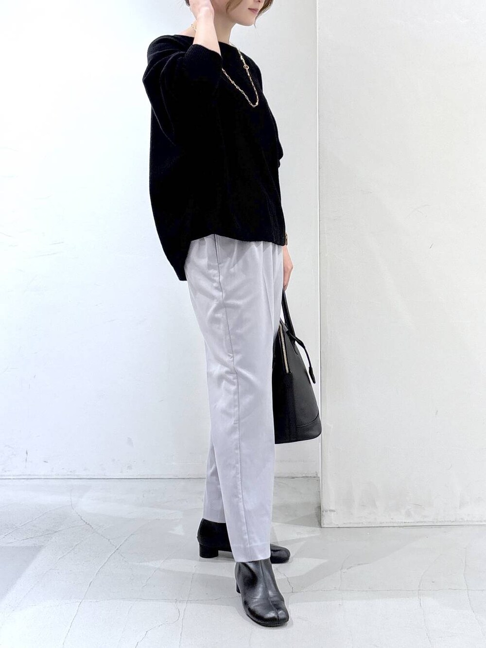 ブラック系のニット/セーター、ブラック系のボストンバッグ、グレー系のスラックスを着用したレディースの秋コーディネートの4枚目の写真