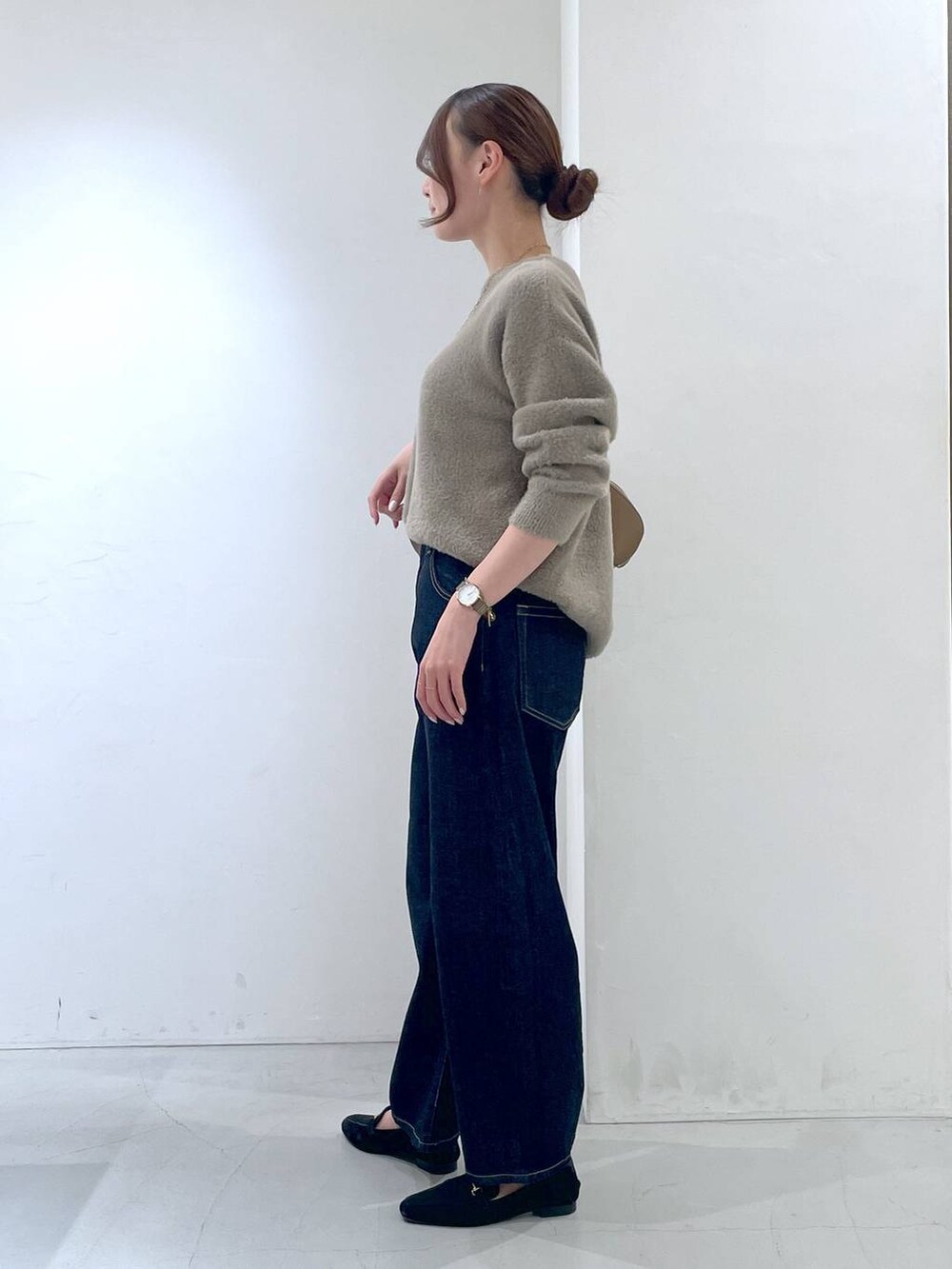 ブルー系のデニムパンツ、イエロー系のトートバッグ、ブラウン系のニット/セーターを着用したレディースの秋コーディネートの3枚目の写真