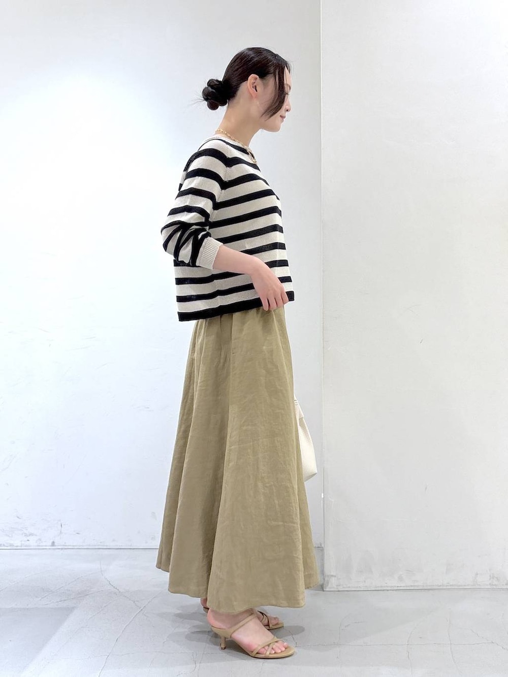 ベージュ系のニット/セーター、ベージュ系のスカート、ホワイト系のトートバッグを着用したレディースの春コーディネートの2枚目の写真