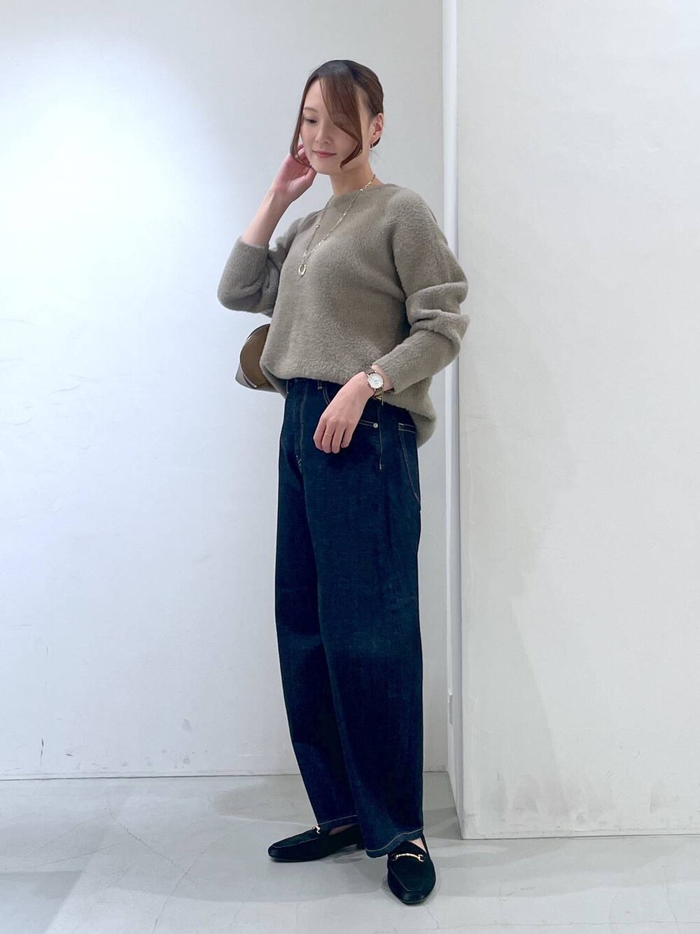 ブルー系のデニムパンツ、イエロー系のトートバッグ、ブラウン系のニット/セーターを着用したレディースの秋コーディネートの2枚目の写真