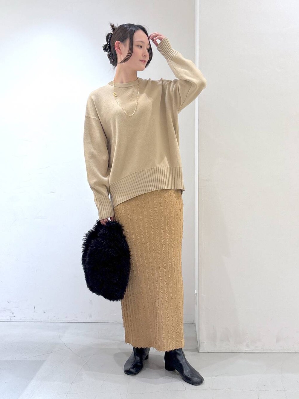 ブラック系のトートバッグ、ベージュ系のスカート、ベージュ系のニット/セーターを着用したレディースの冬コーディネートの2枚目の写真