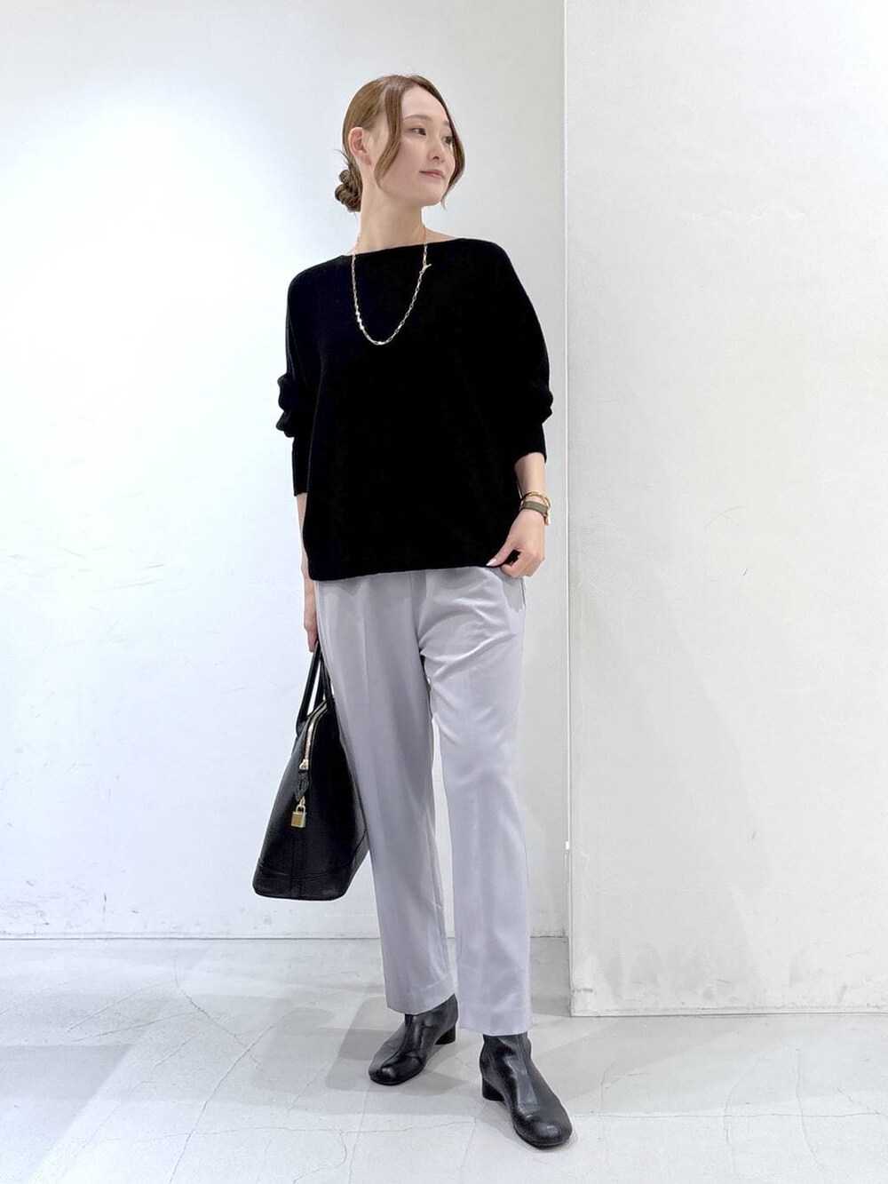 ブラック系のニット/セーター、ブラック系のボストンバッグ、グレー系のスラックスを着用したレディースの秋コーディネートの2枚目の写真