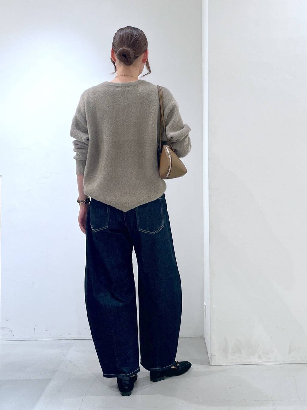 ブルー系のデニムパンツ、イエロー系のトートバッグ、ブラウン系のニット/セーターを着用したレディースの秋コーディネートの4枚目の写真