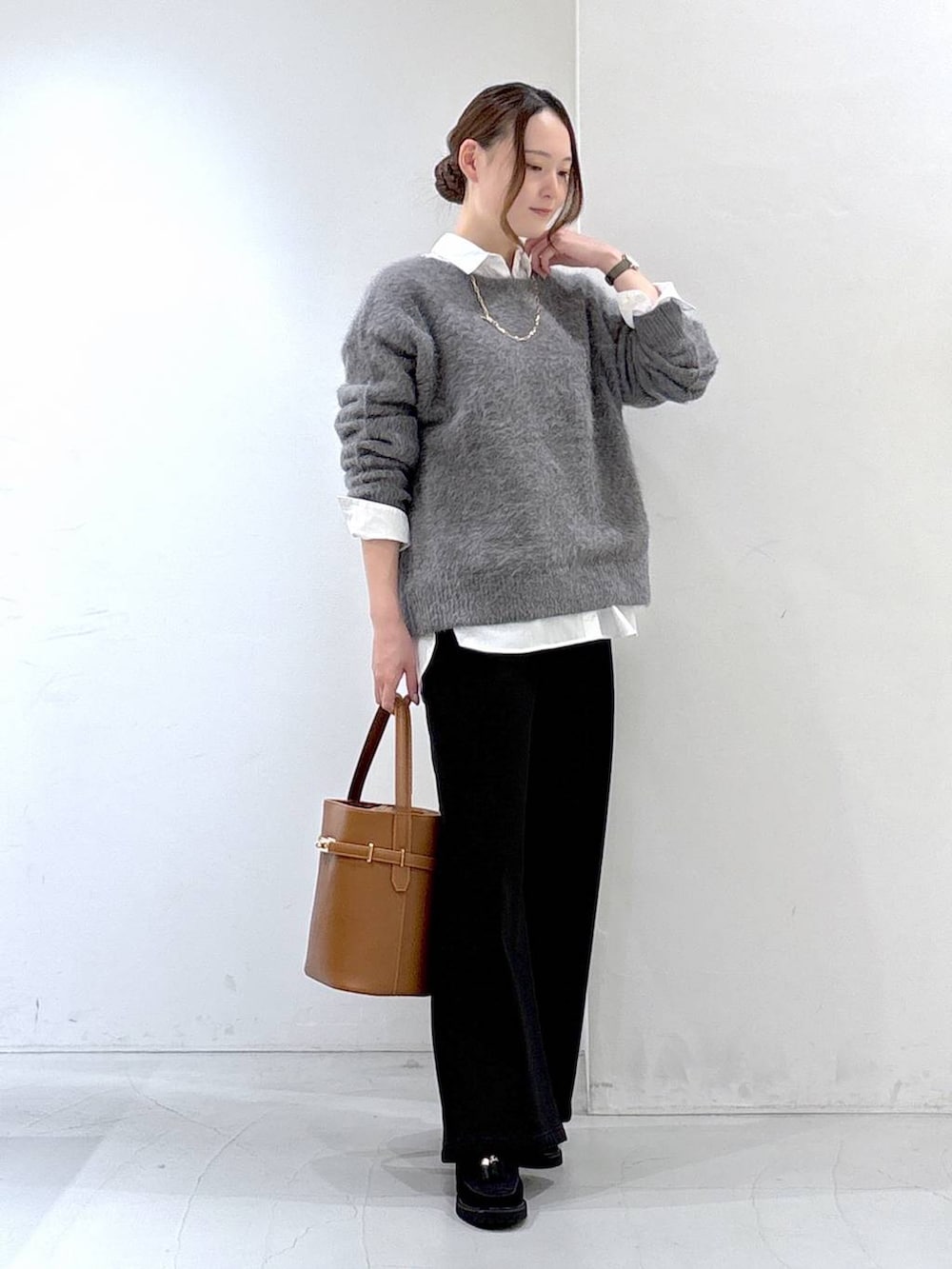 グレー系のニット/セーター、ホワイト系のシャツ/ブラウス、ブラック系のデニムパンツを着用したレディースの秋コーディネートの2枚目の写真